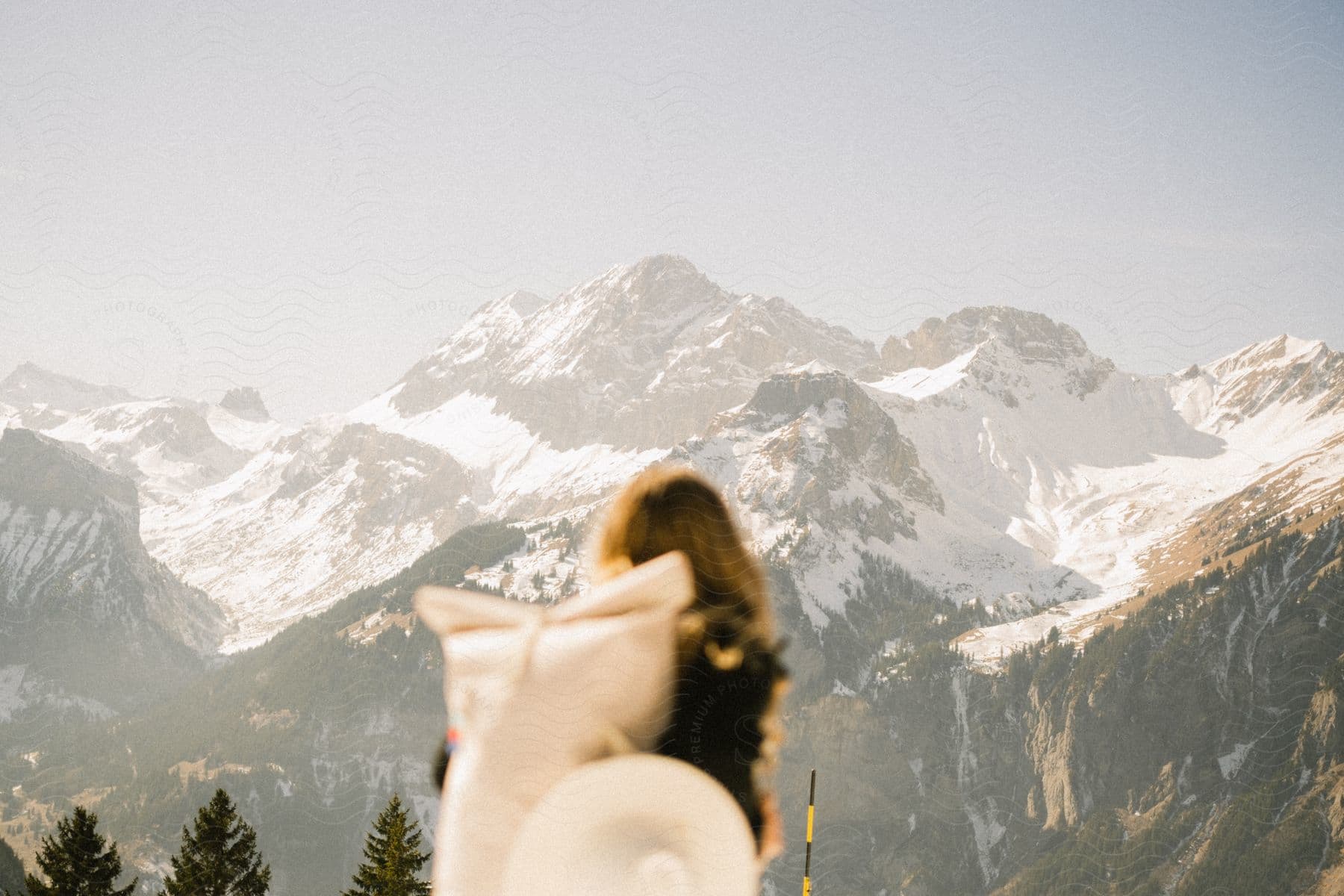 Backpacker stands looking at snow covered mountains.