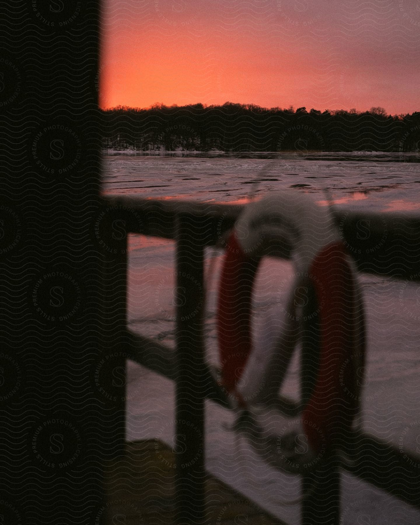 A red and white life preserver hangs on a ferry boat's metal railing, overlooking a body of water.