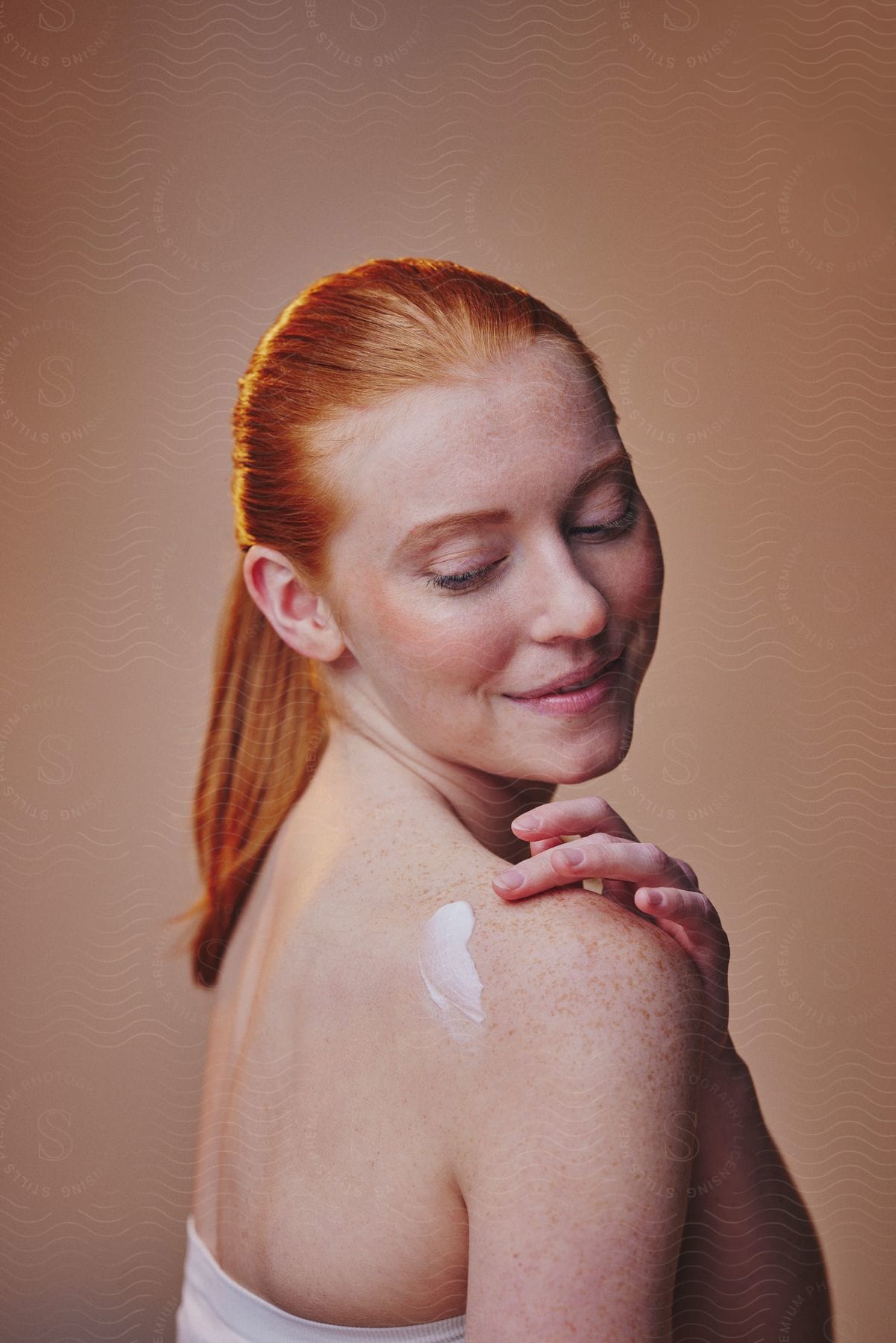 A woman putting lotion on her shoulders