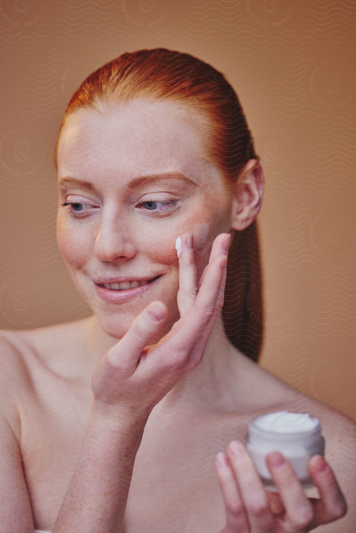 A woman putting some lotion on her face