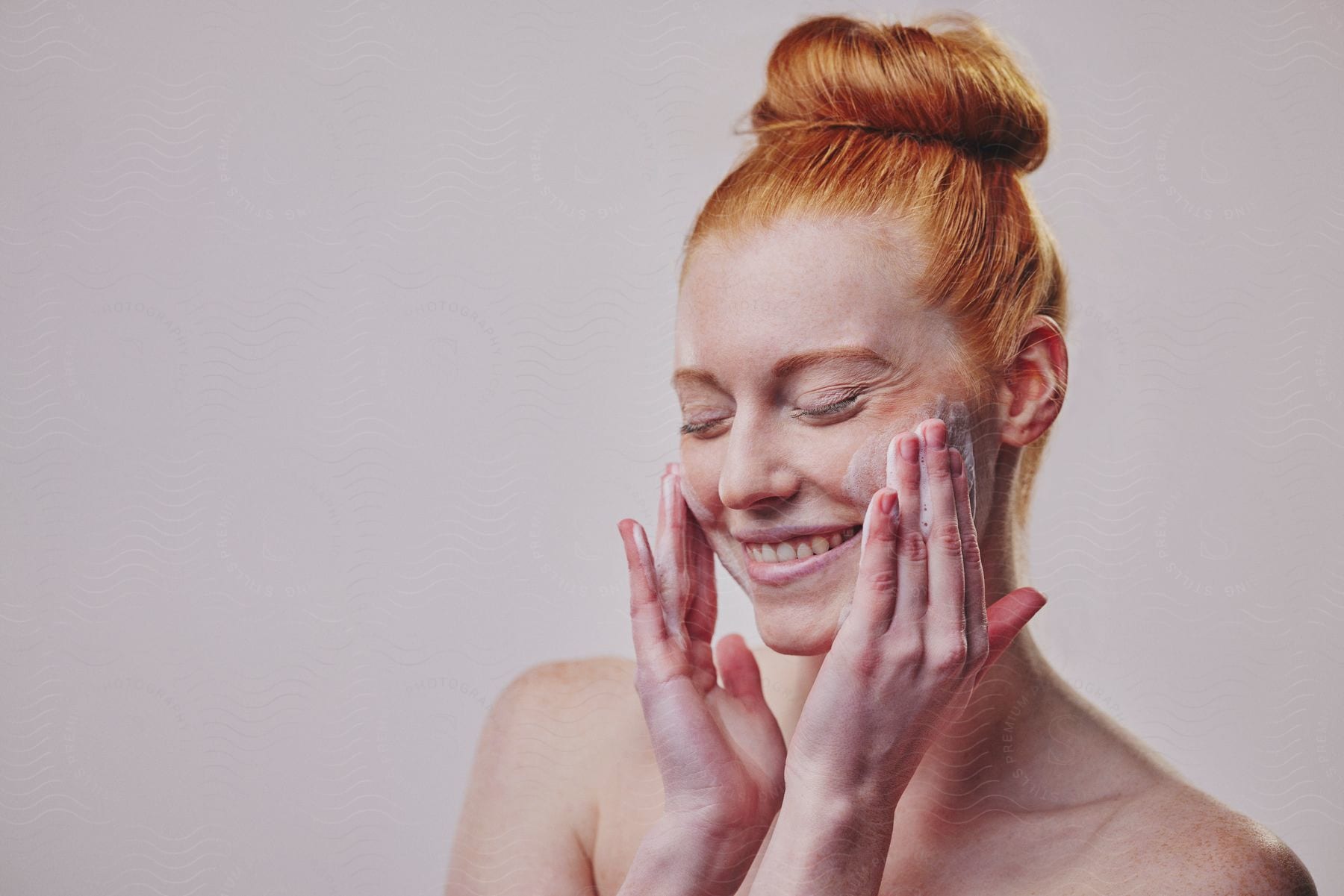 A woman gently applying face cream to her face.