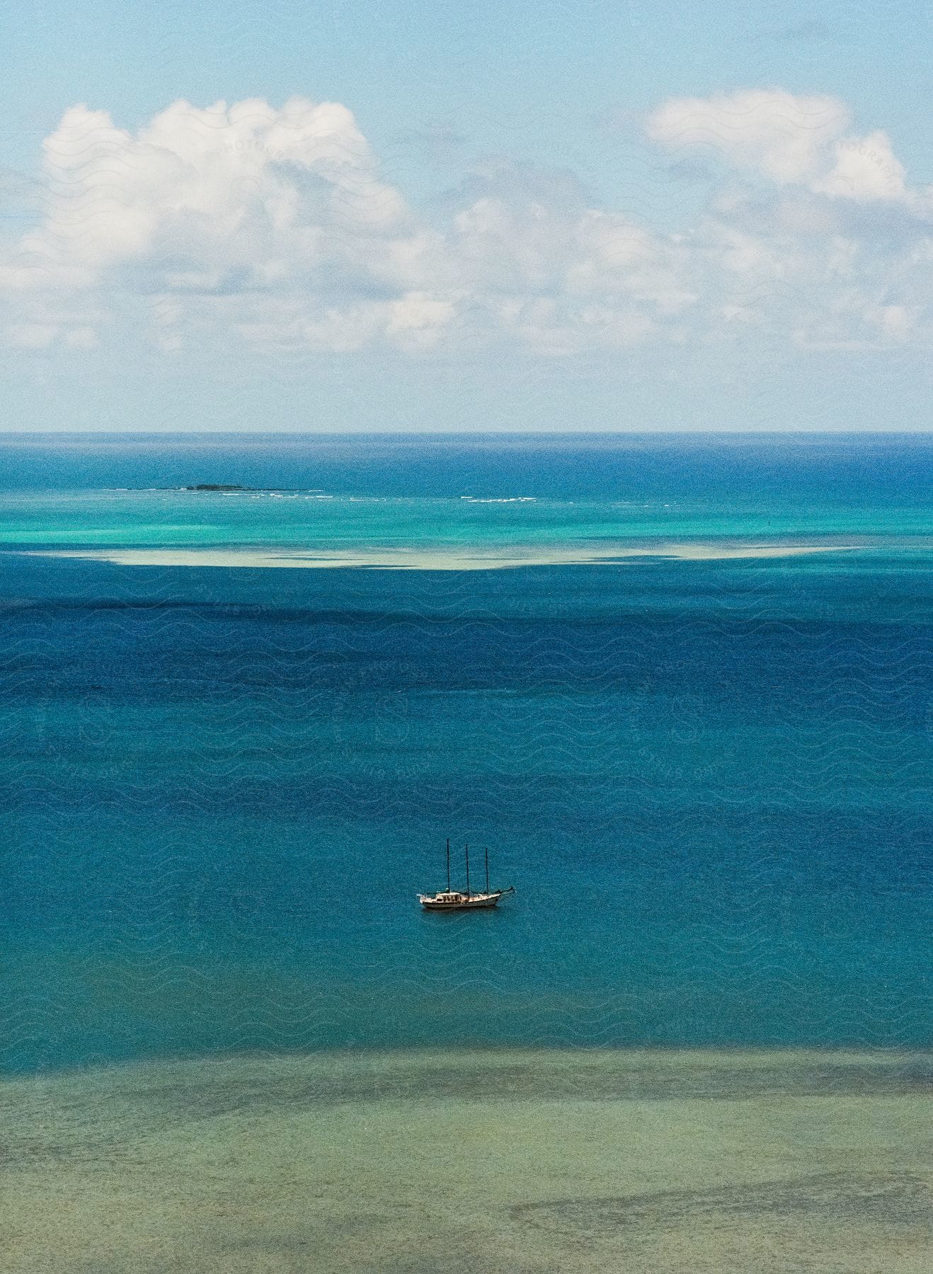 A small sailboat glides across a vast blue ocean