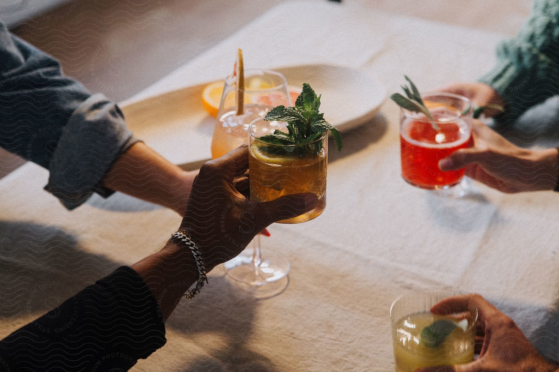 a group of men wearing shirts with folded sleeves holds up beverages to clink