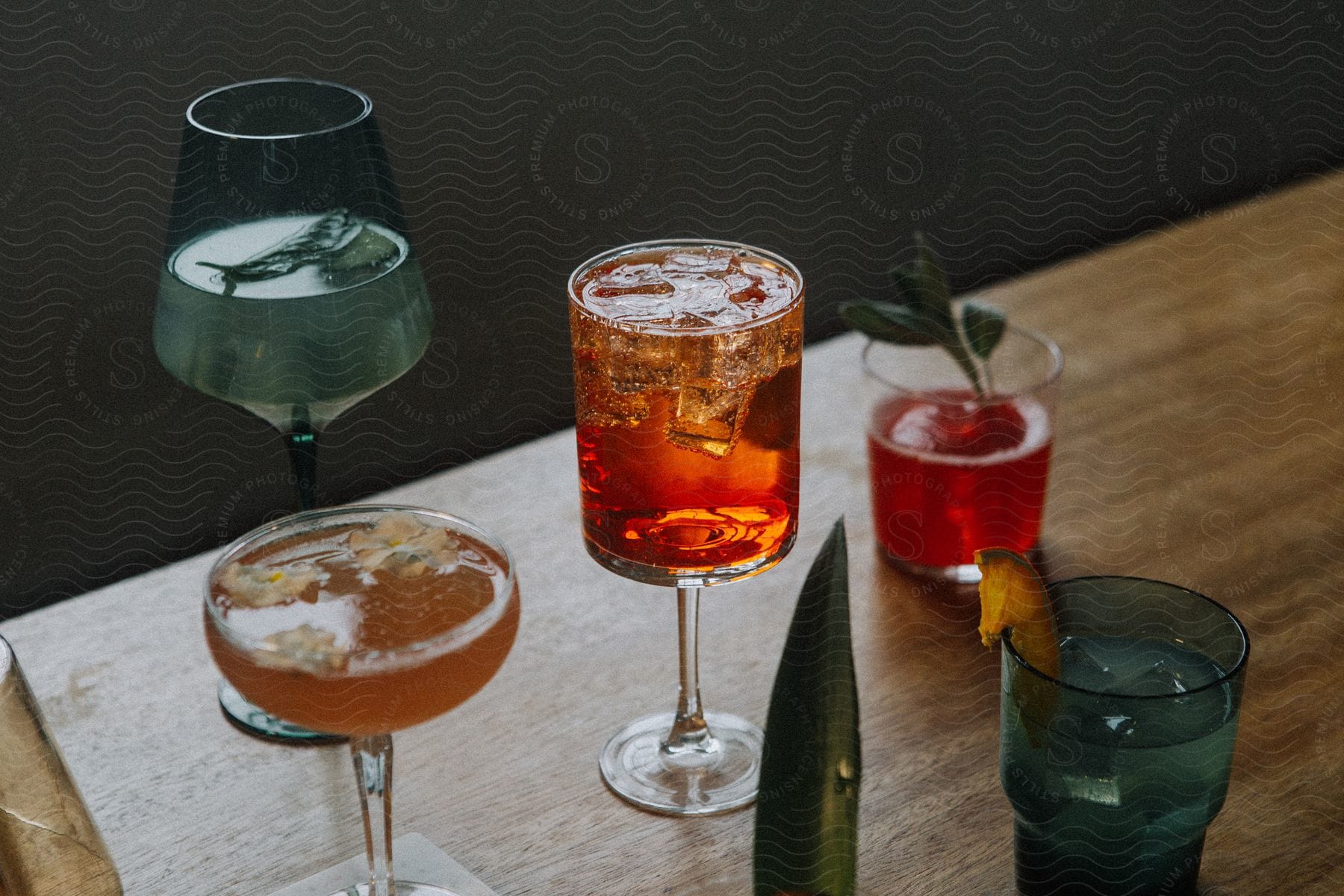 Stock photo of a table with several different glasses of colorful drinks and some fruit and ice