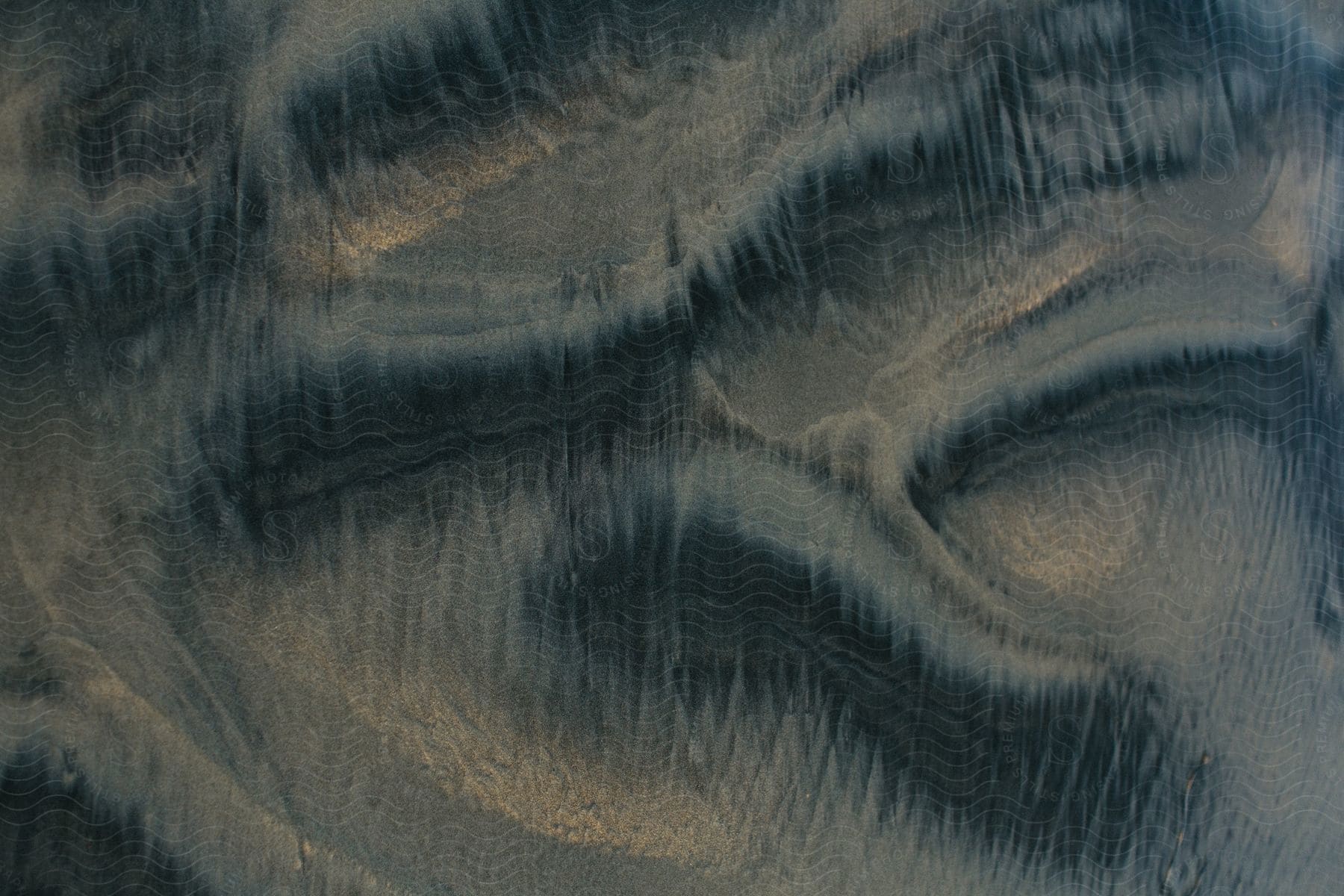 an aerial view of a beige-colored sandy soil and some dark parts