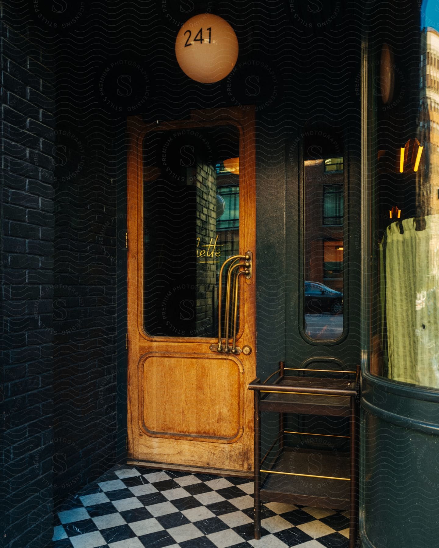 a closed wooden door with a metal handle, mounted on a black and white checkered floor.