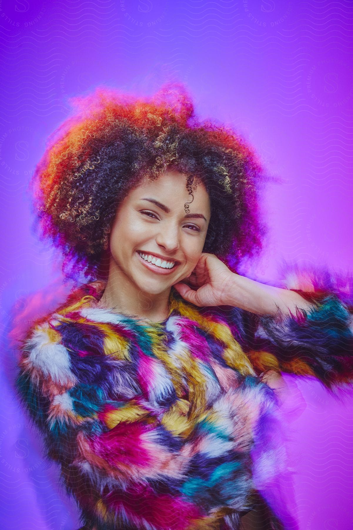 Smiling model woman with curly hair and wearing a colored fur blouse against a violet purple background