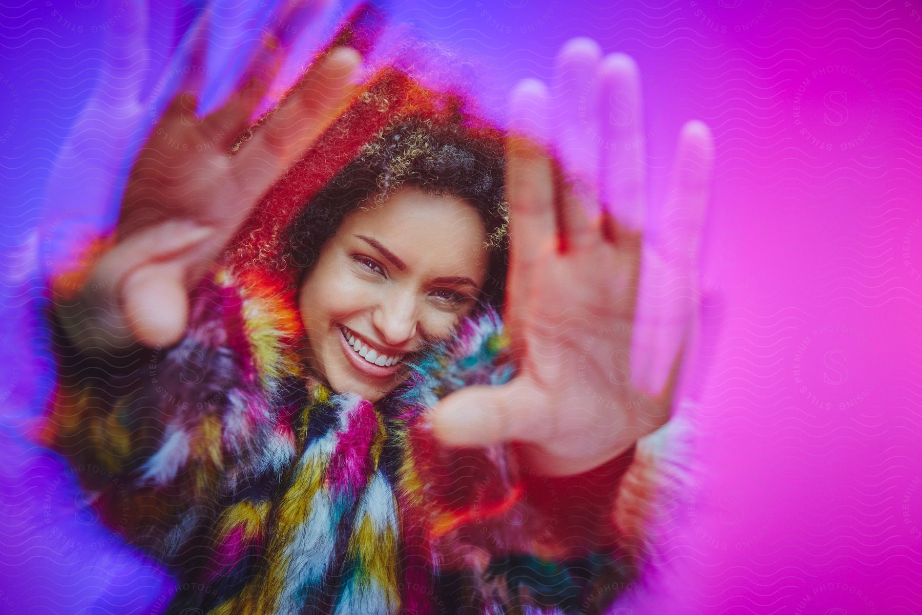 A woman laughs while stretching her hands forward, surrounded by shades of pink and blue.