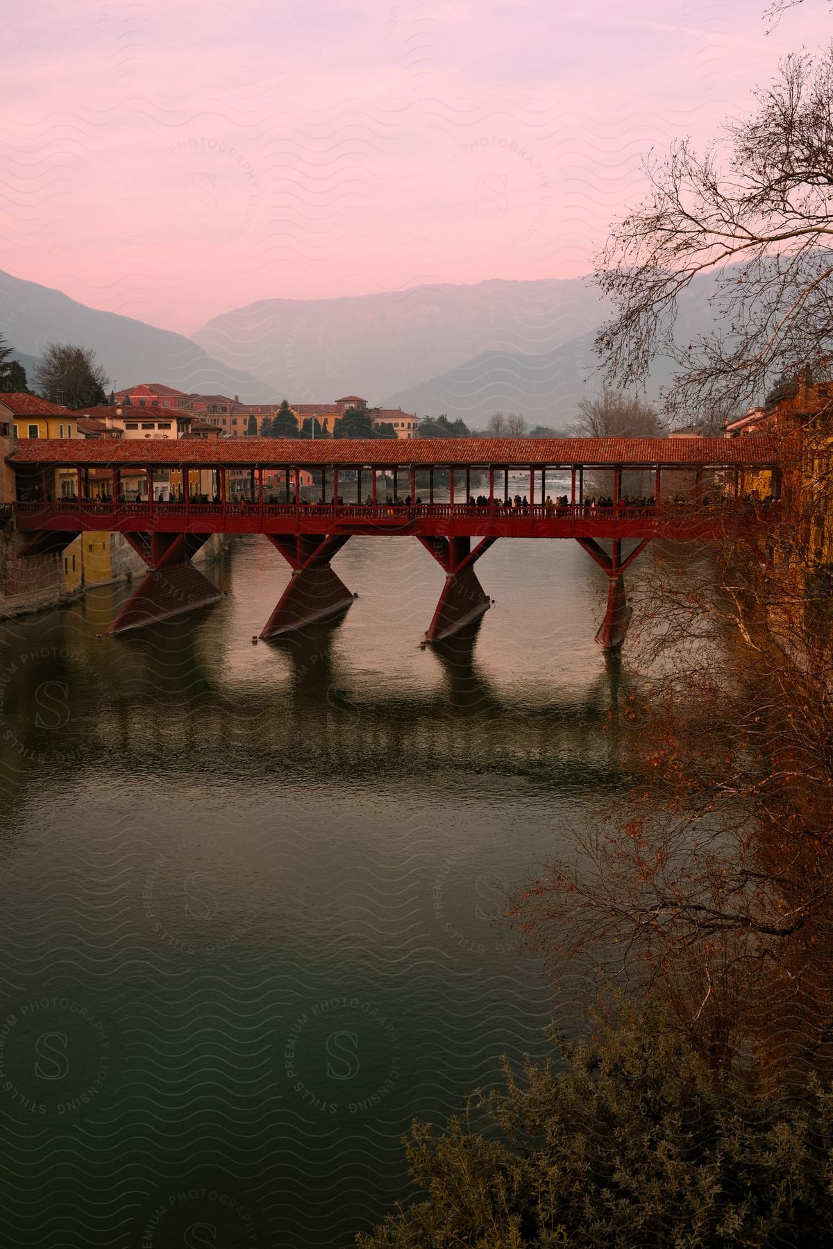 A steel crossing bridge filled with people crossing at sundown.