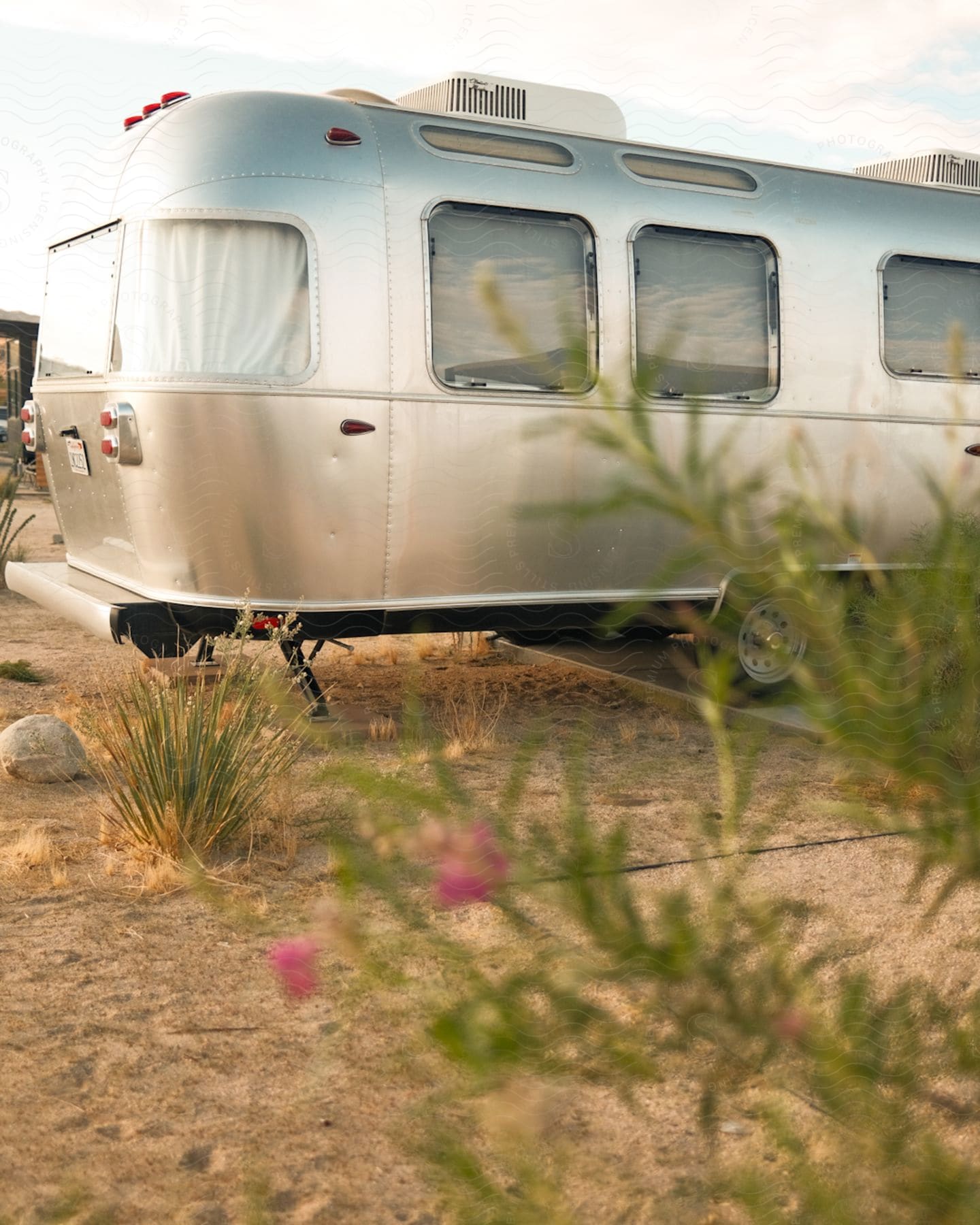 Vintage airstream travel trailer parked outdoors over a sand covered lot