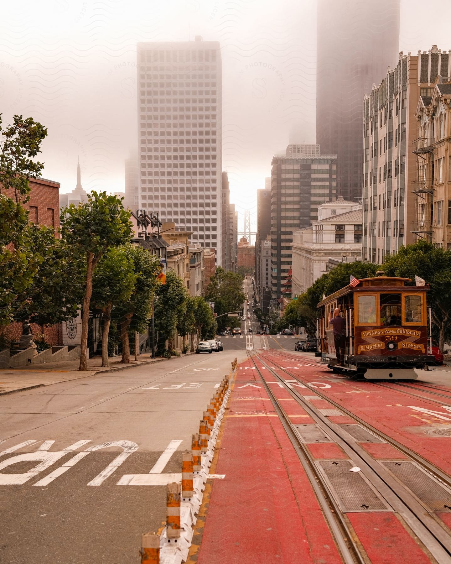 Panorama of an asphalt street with a cable car on the track and large buildings of a metropolis in the background on a cloudy day.