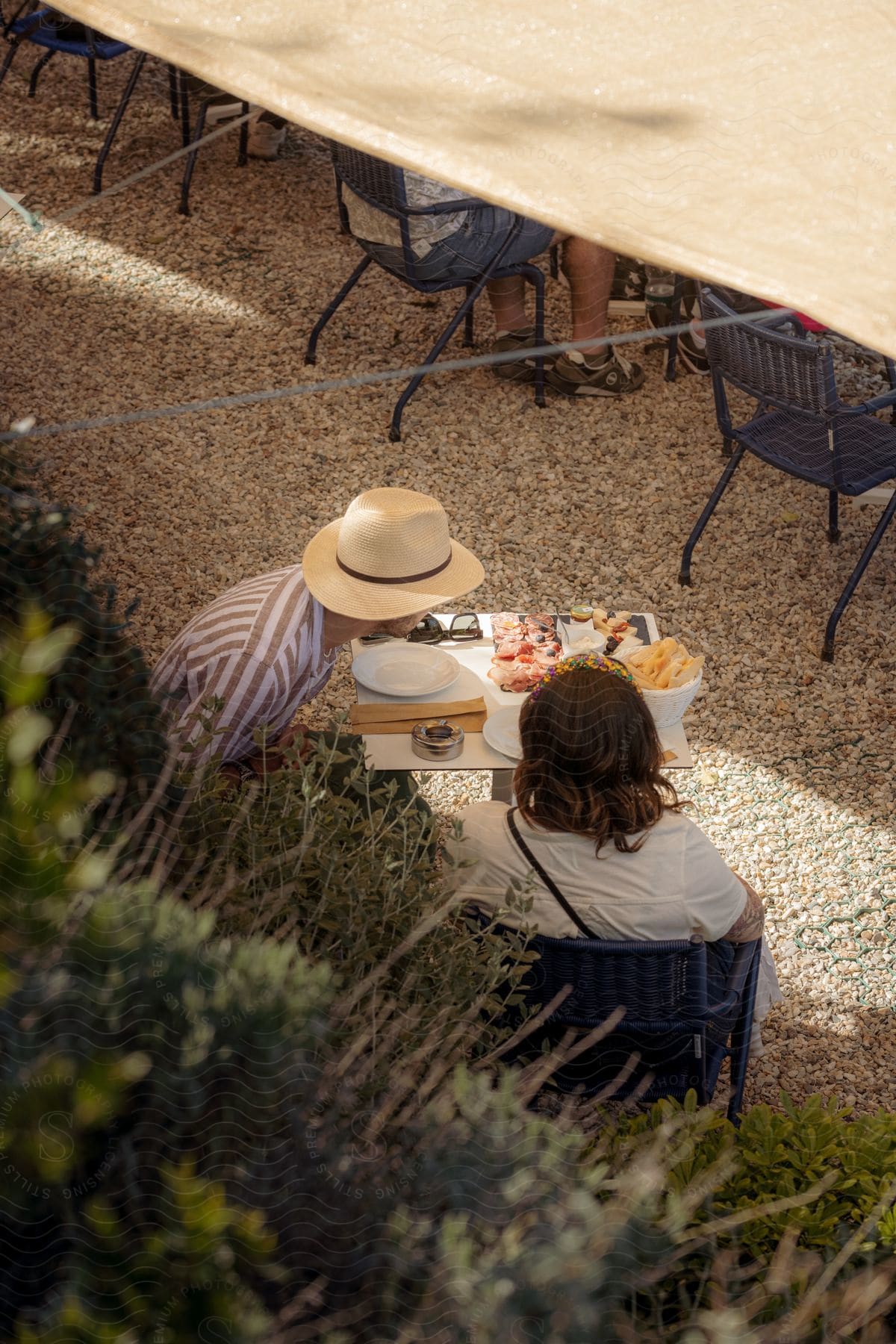 A man and woman having some food outdoors at a restaurant