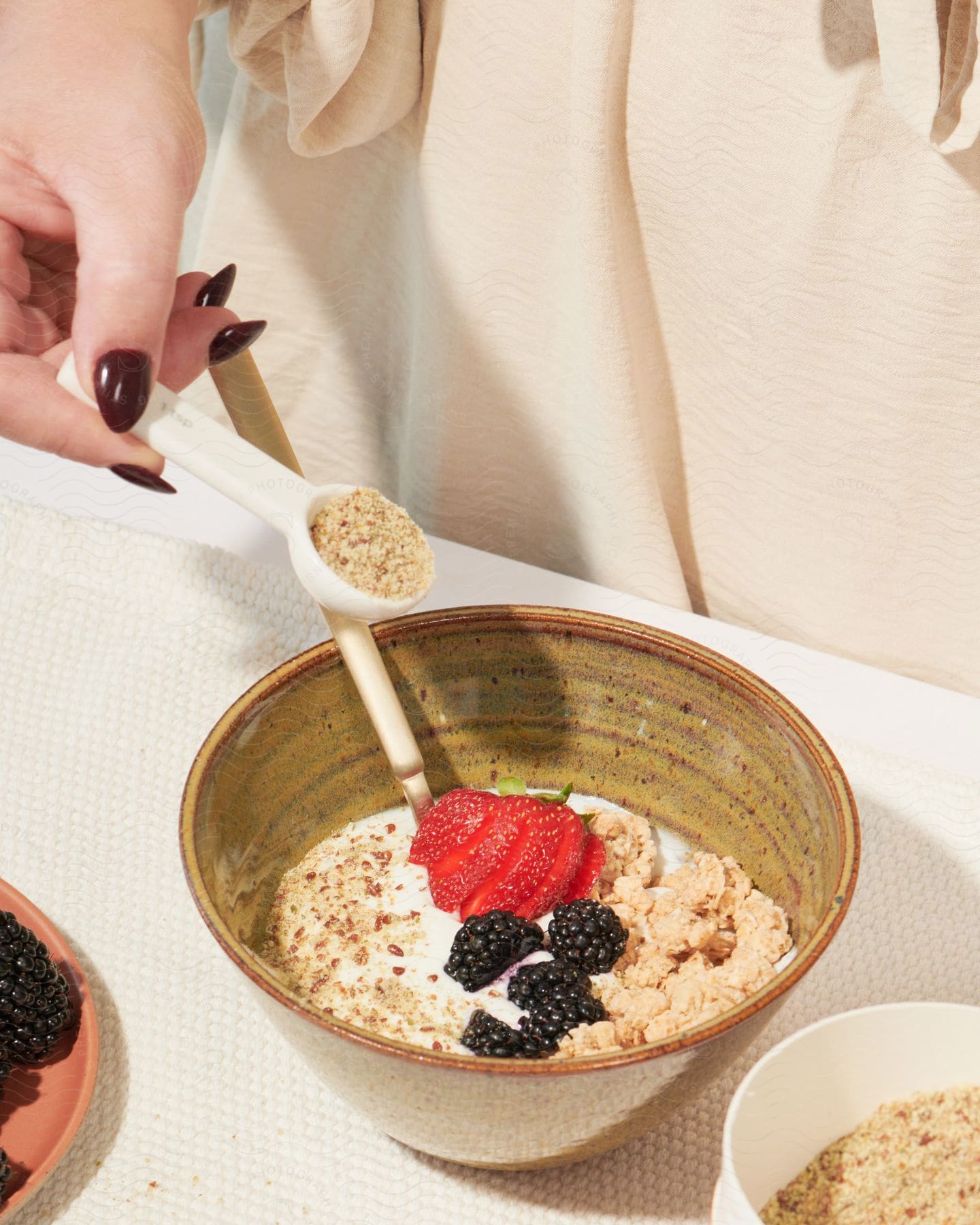 Woman's hand putting cereal in a bowl with yogurt and fruit