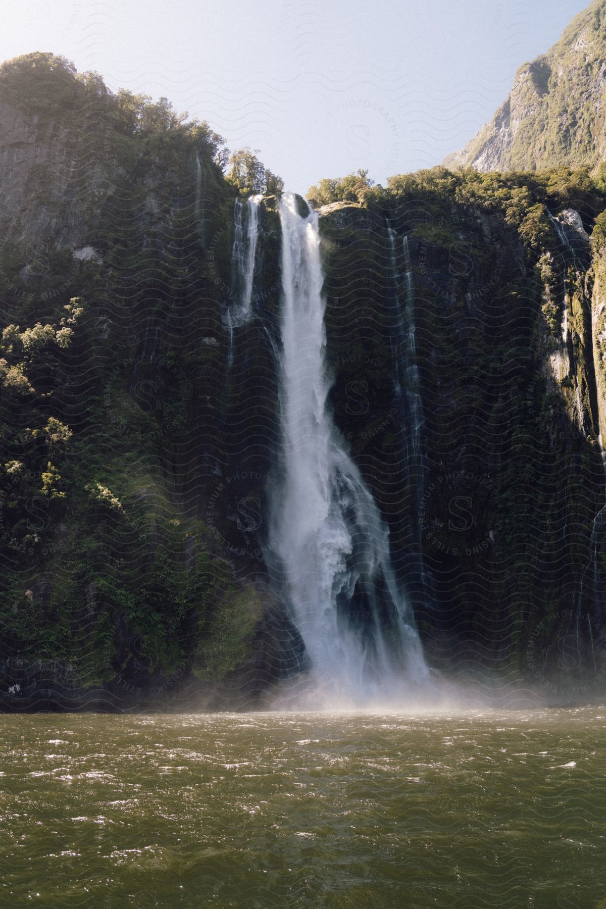 A waterfall that comes out of a rock wall and falls into a body of water