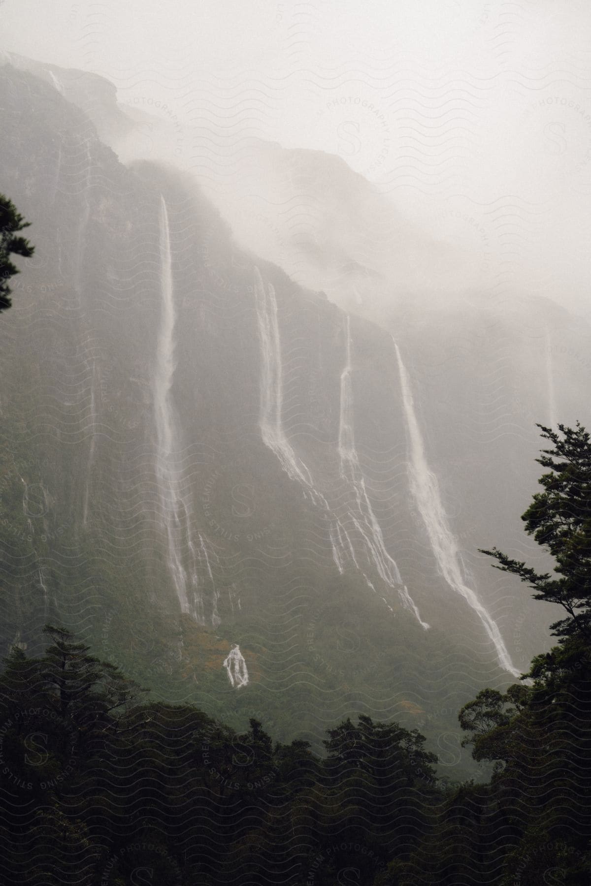 Streams of water flow over a mountain under a cloudy hazy sky