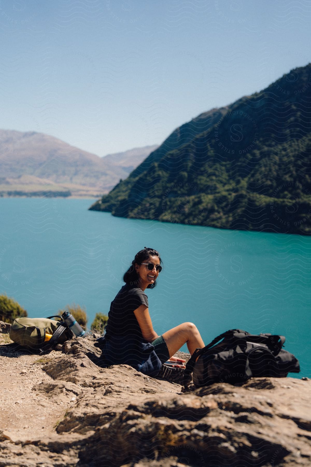 A smiling Indian woman sits near a coast