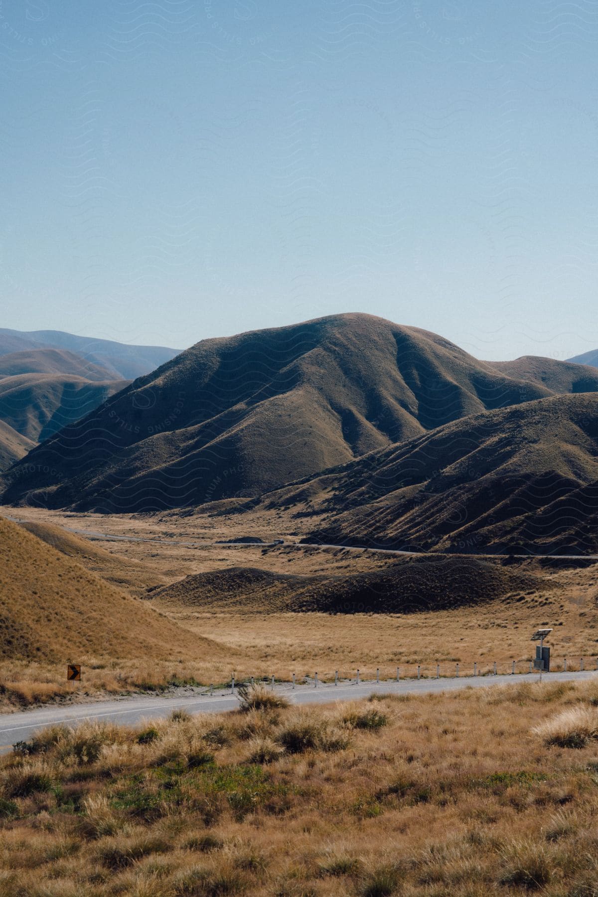 A road going past rolling grassy hills.