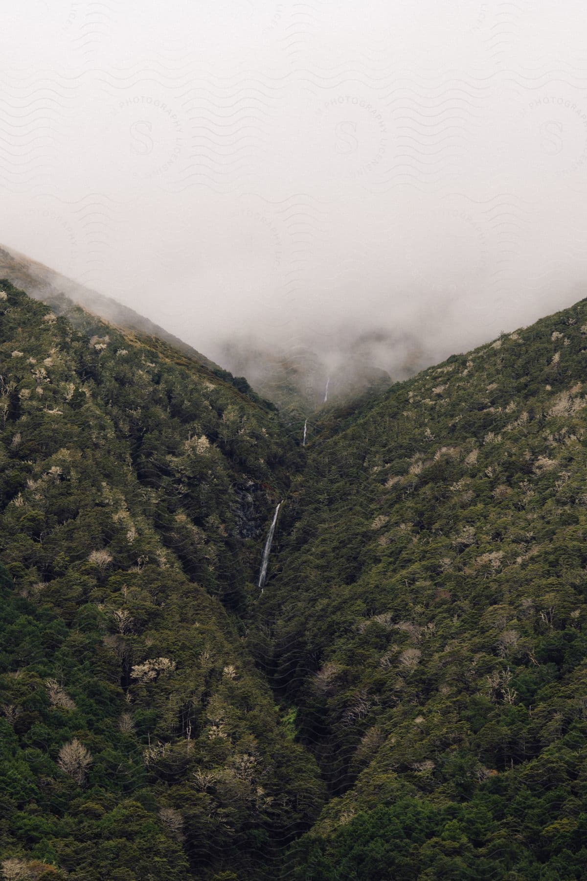 A view of a mountain range with some clouds at the top of it