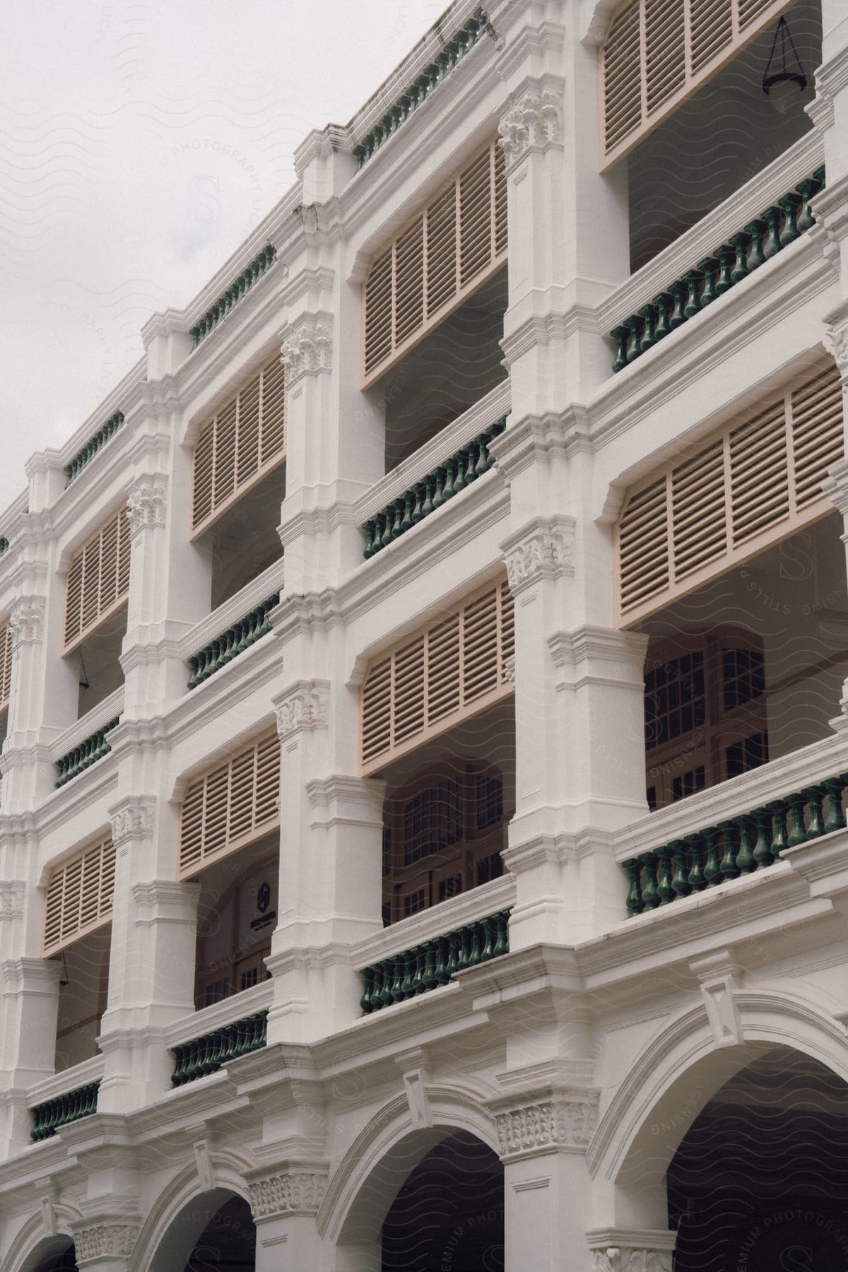 A multi-story concrete building has several archways and balconies.