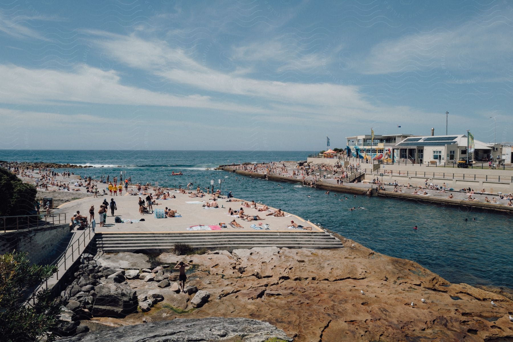 Several people sunbathing and diving in the water on a sea coast