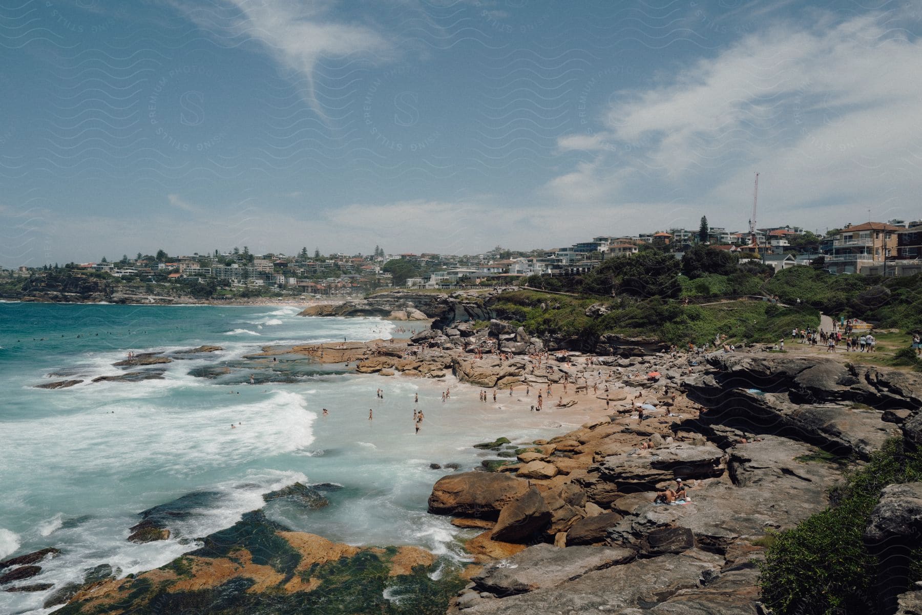 Panorama of a beach with rocky coastline with sunbathers on a summer day