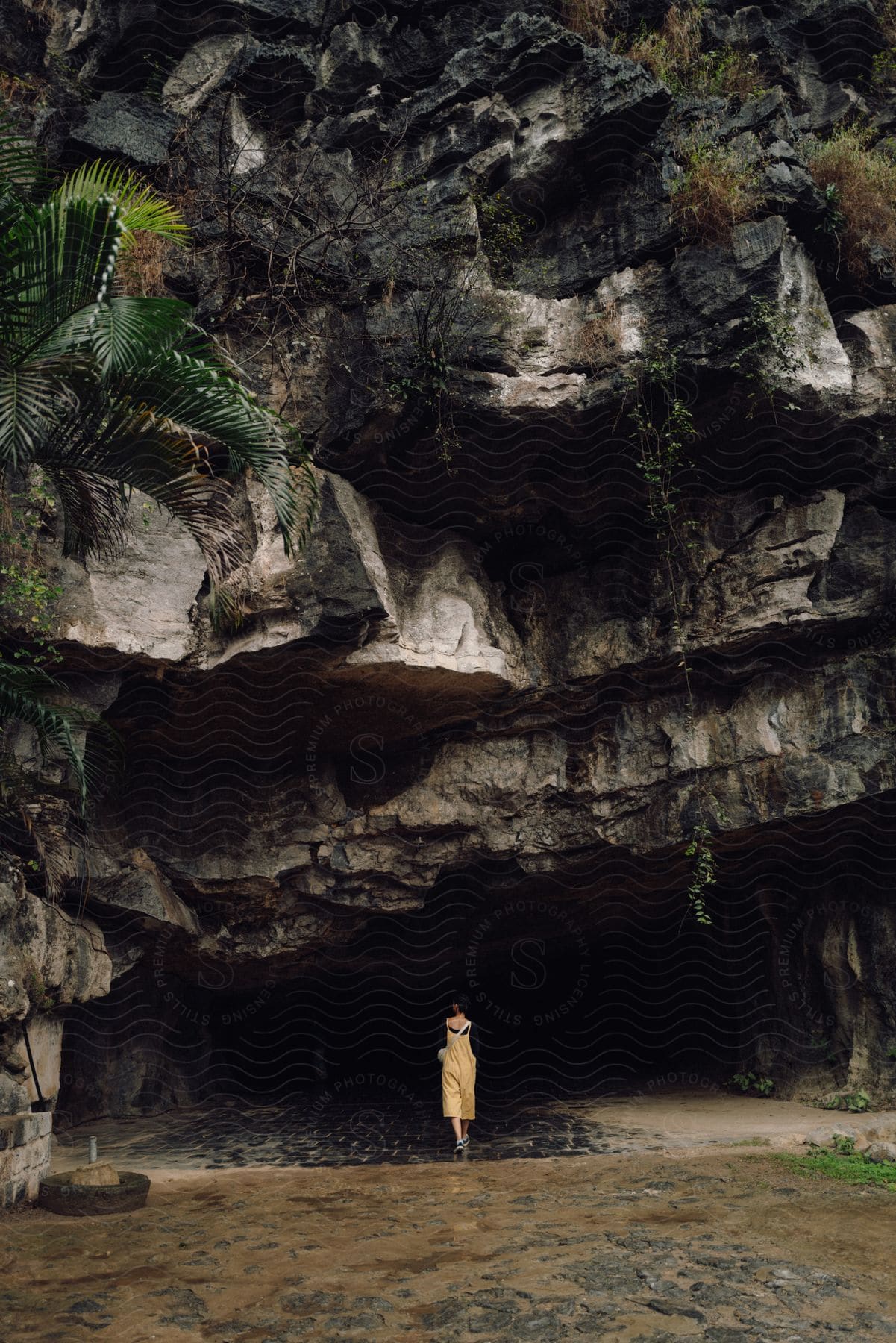 Woman walking towards a rocky cave during the day