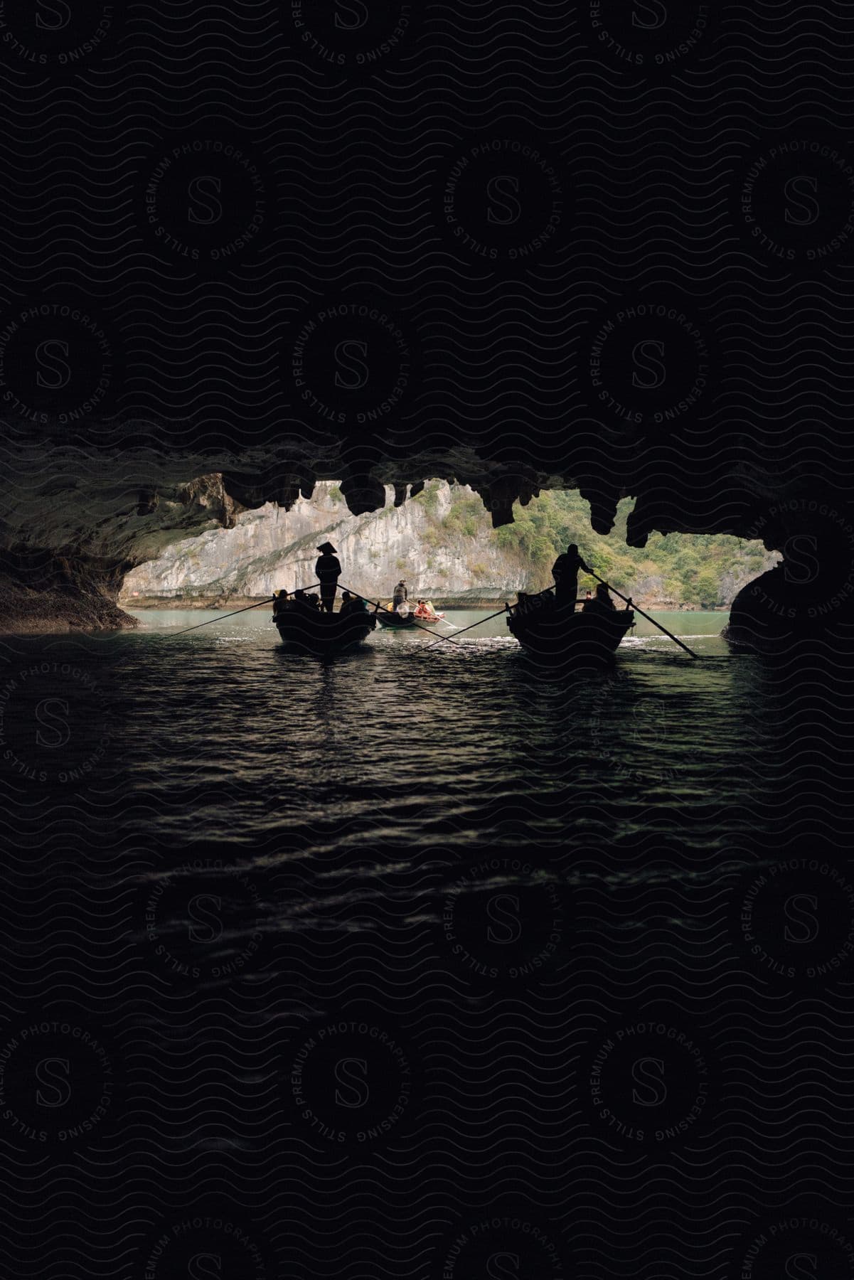 Silhouette of two boats with tourists passing by in a cave