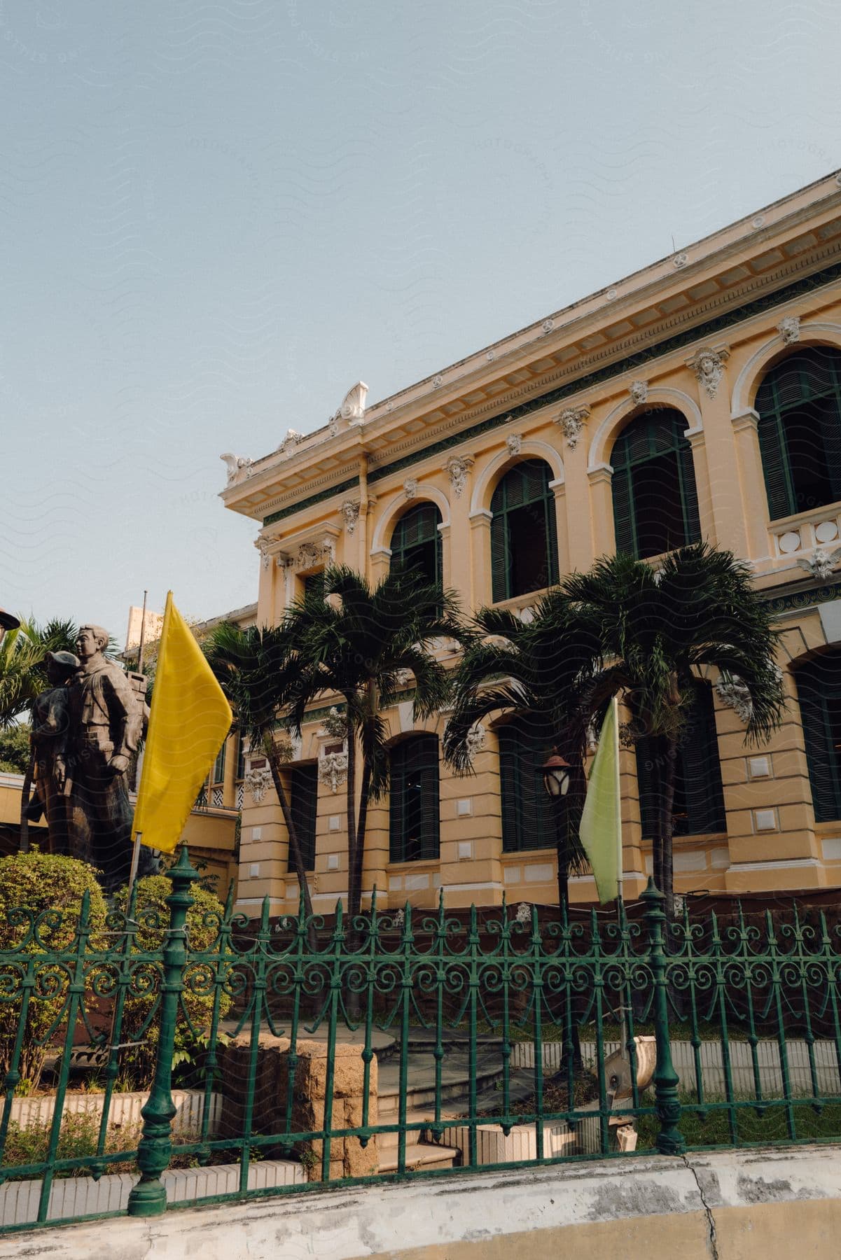 The fenced front yard of a classically designed official building.