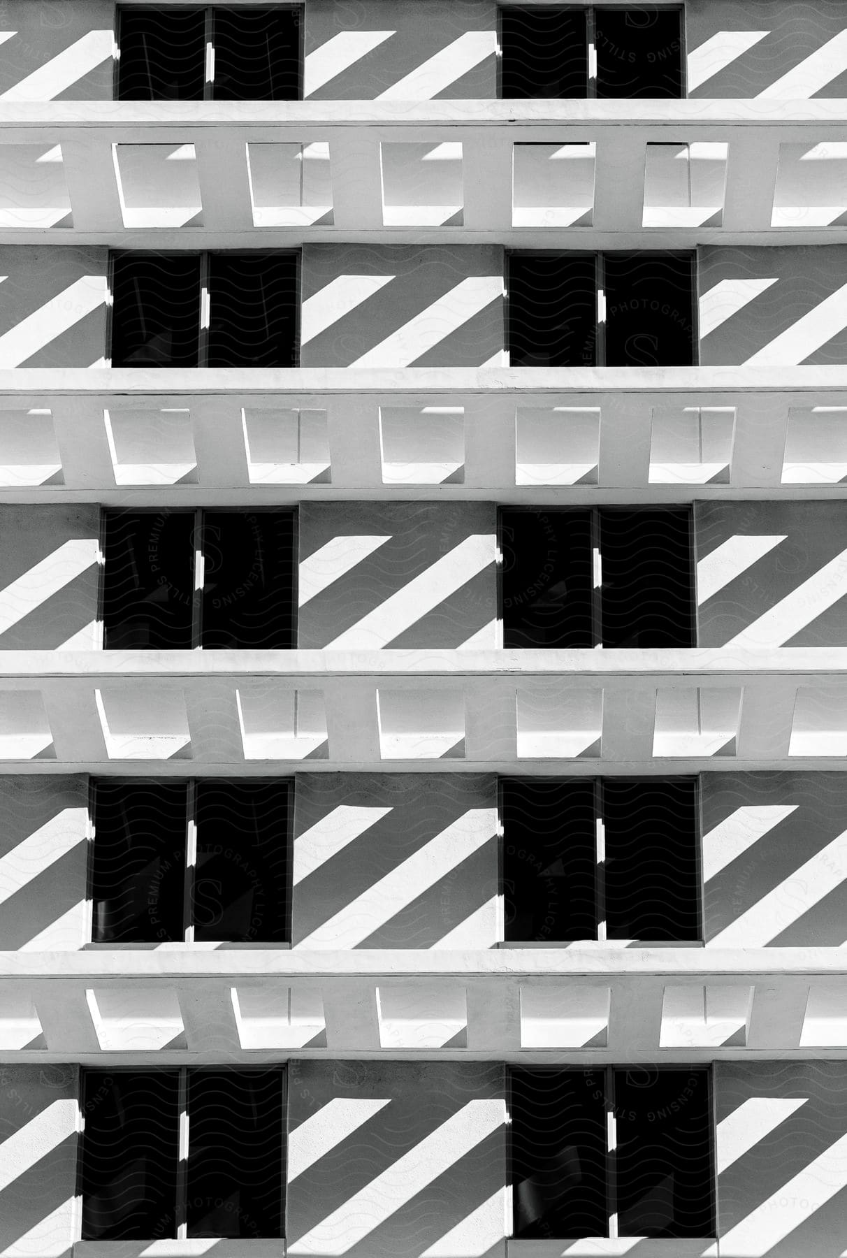 Facade of a white building with a repeating pattern of balconies and shadows.