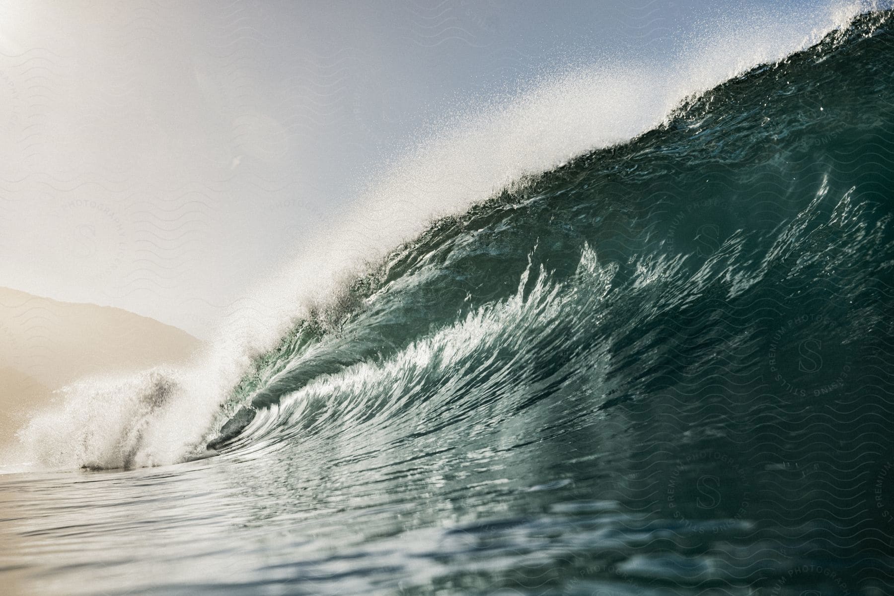 Strong wave about to break and the coast in the background one morning.