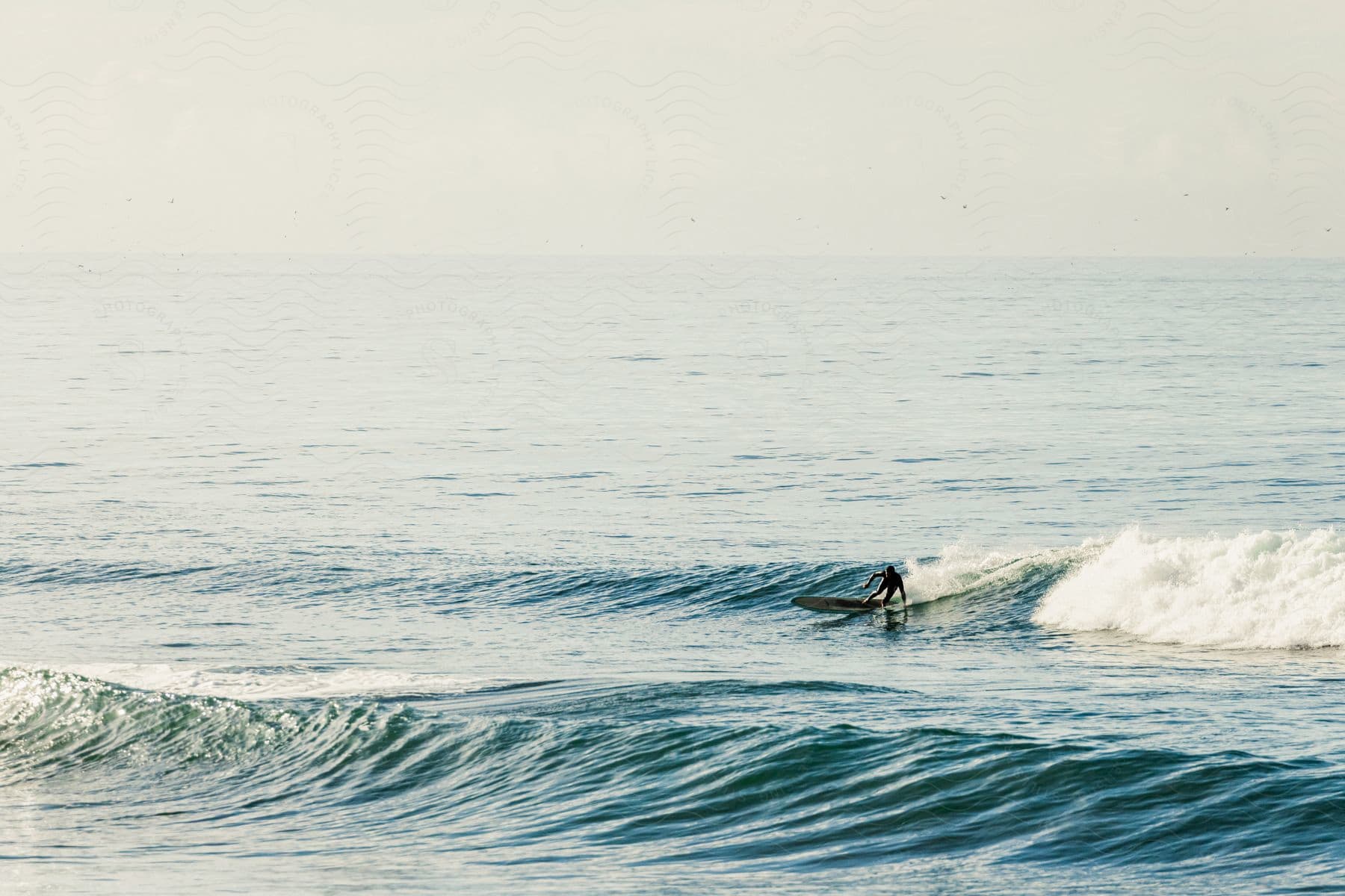 An adult surfs an ocean wave on a cloudy day.