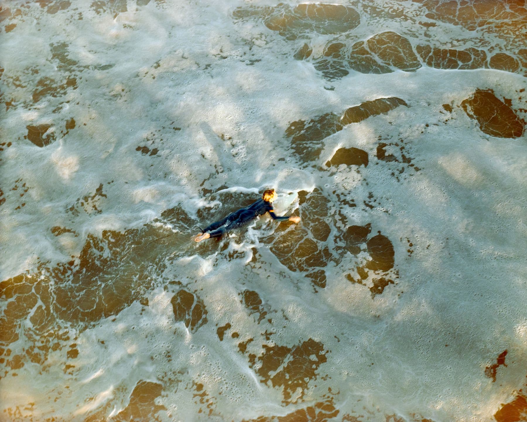 An aerial image of a person swimming at the sea bank