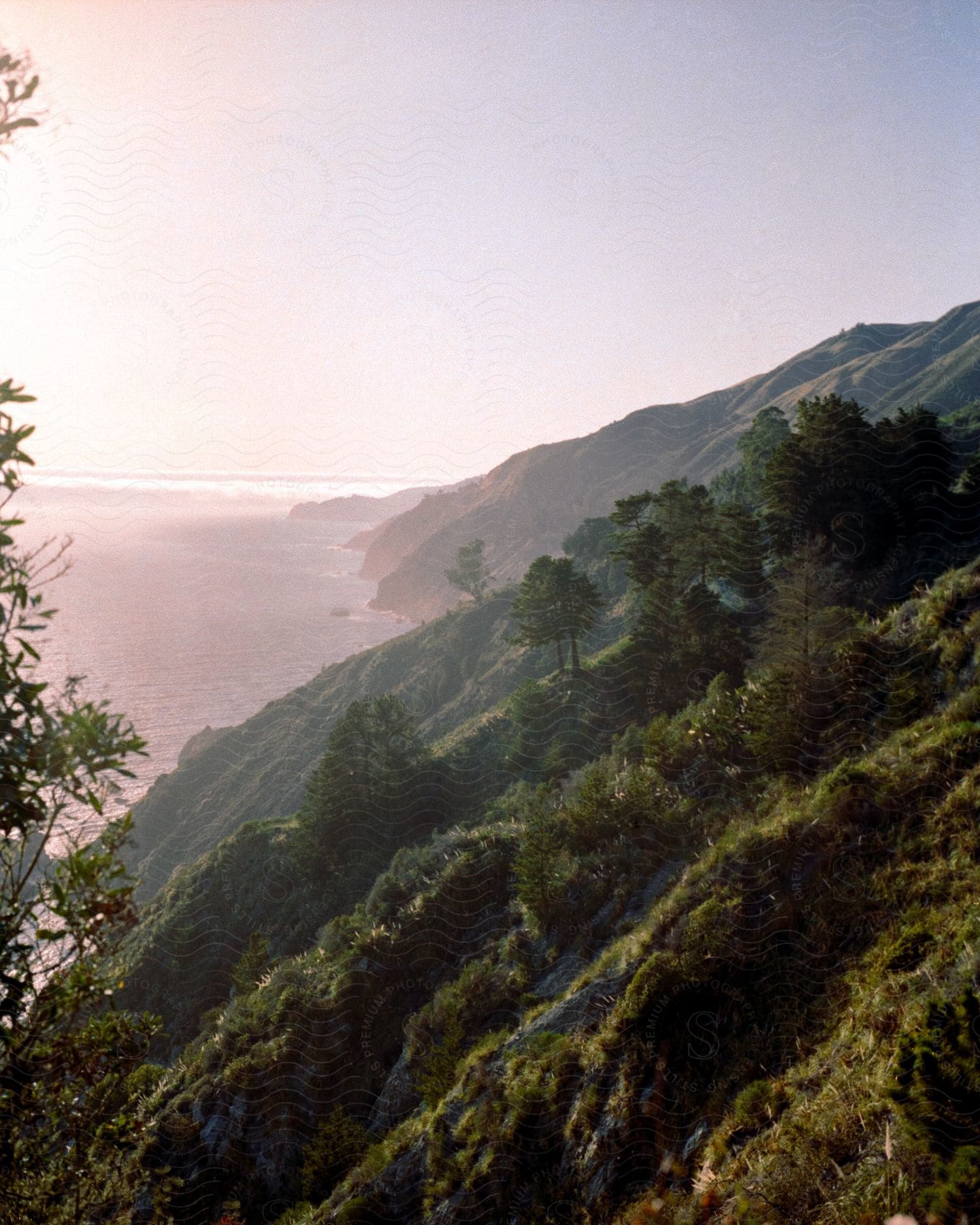 A serene view of a mountainous coast bathed in sunlight.