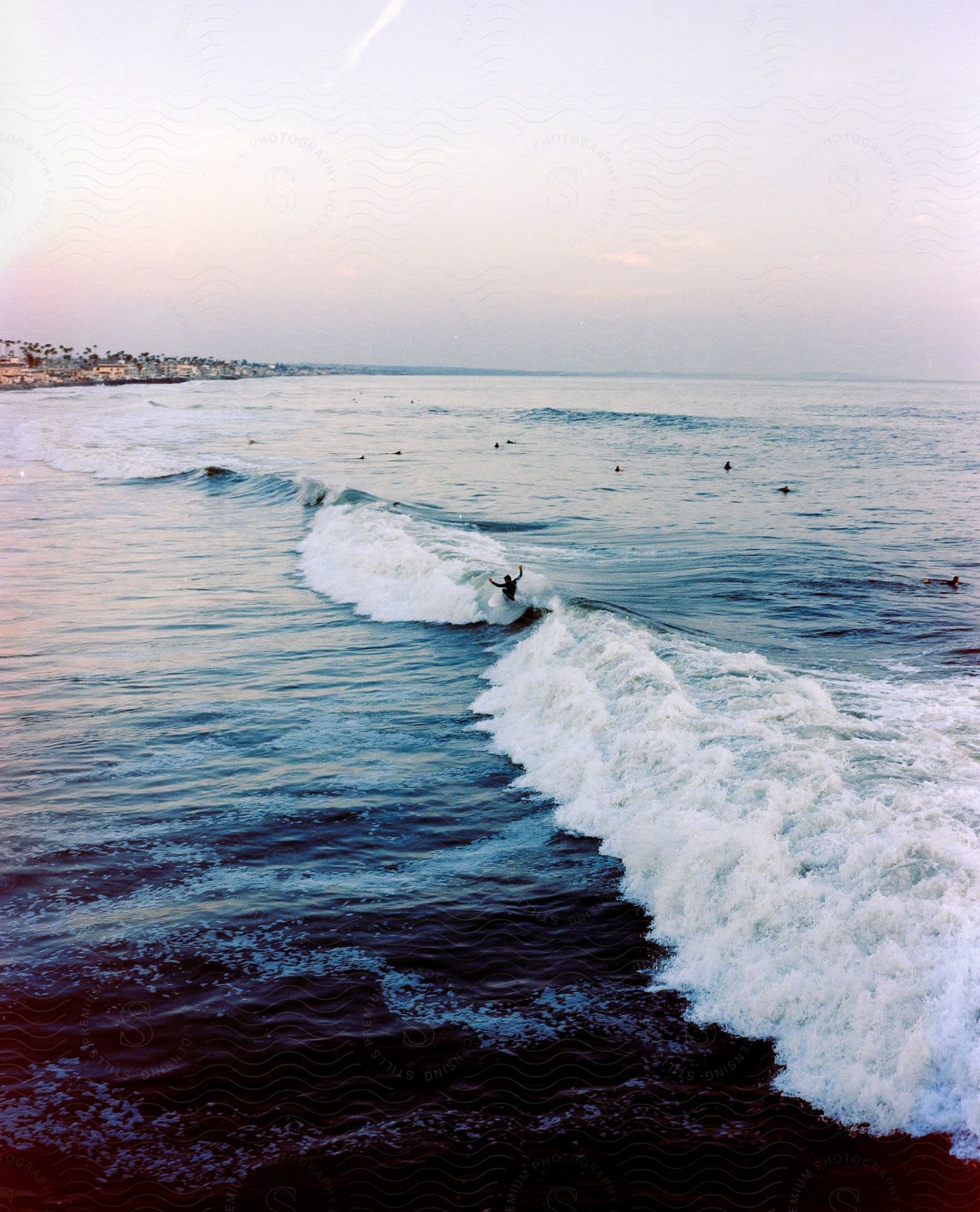 Person surfing a wave in a morning with other surfers at sea