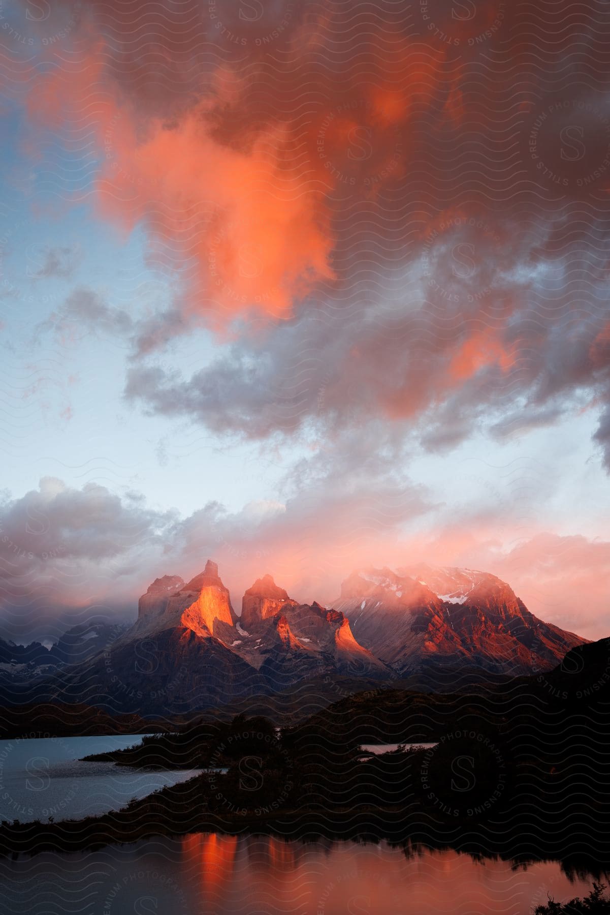 Sunlight shines on mountains along the coast and reflects on the clouds and the water