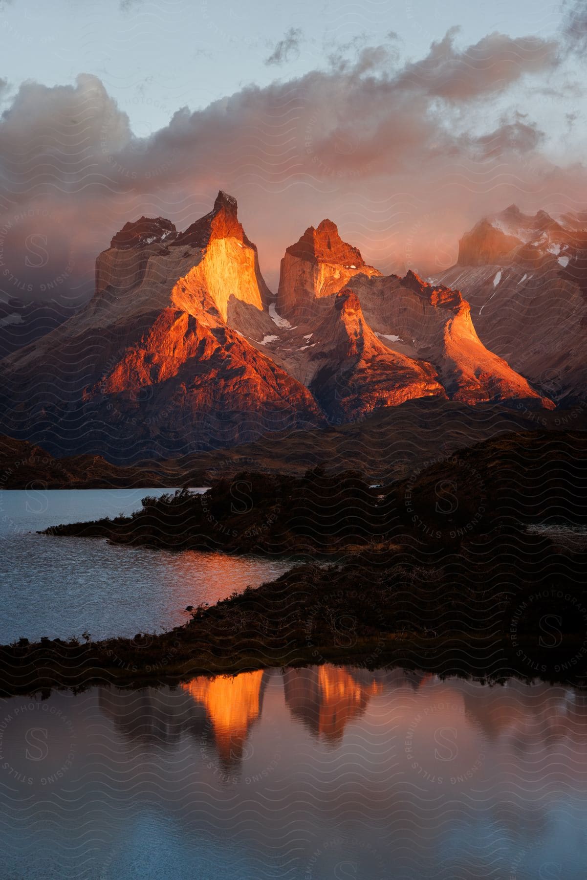 Landscape of rocky mountain ranges by a lake in a reddish morning sky