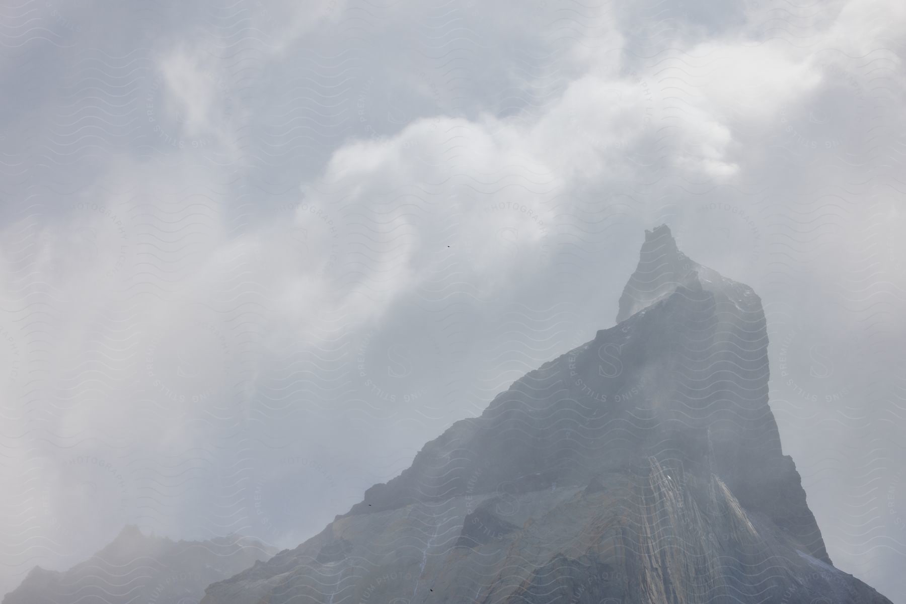 A steep mountain peak emerging through a thick layer of mist.