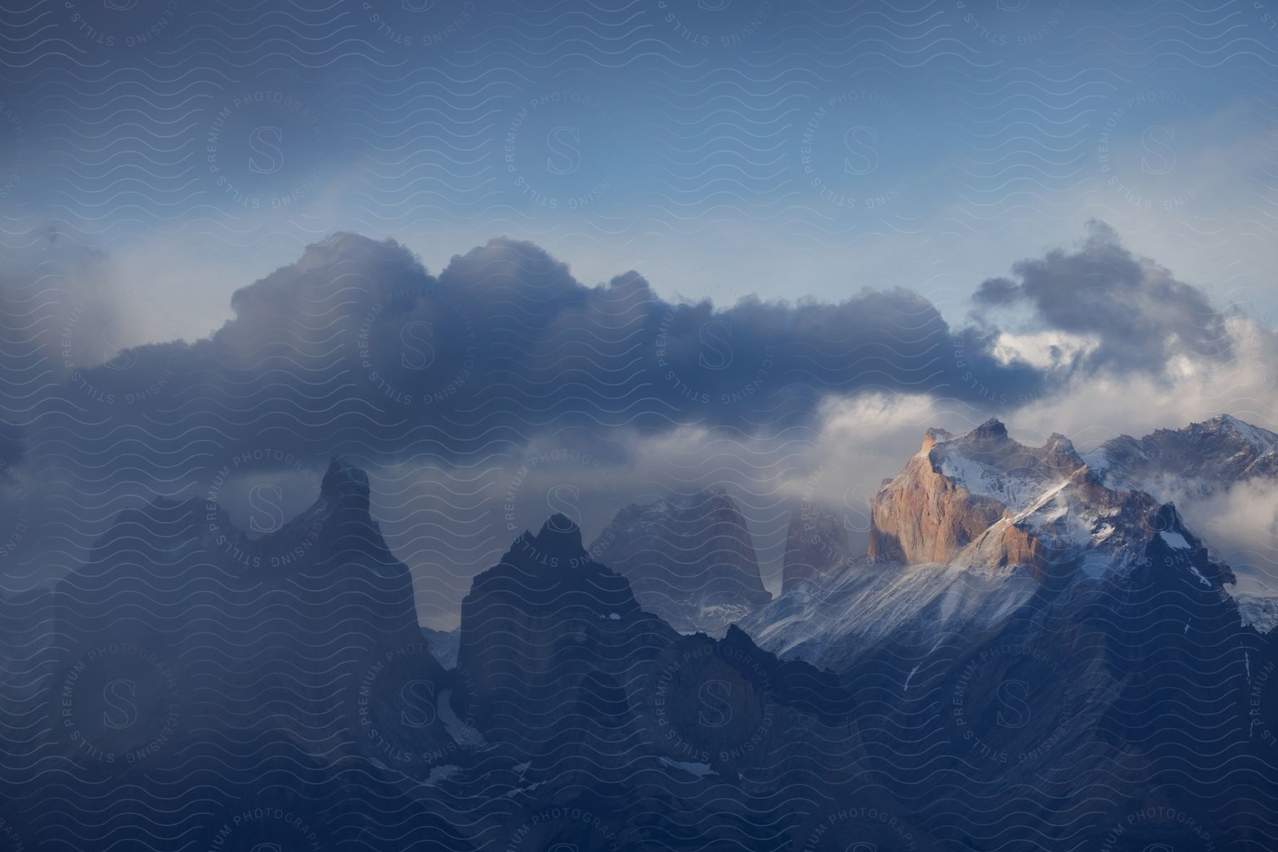 Stormy clouds hover over snow-capped mountains.