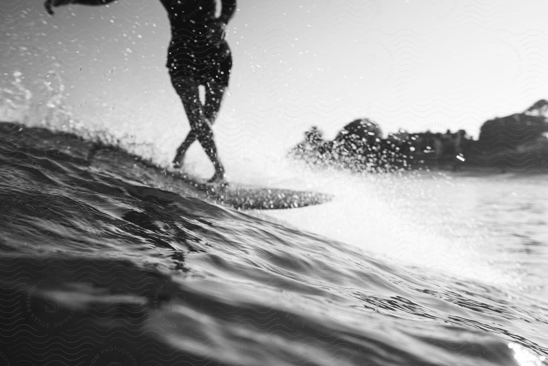 A black-and-white photo of a surfer catching a wave with splashes of water.