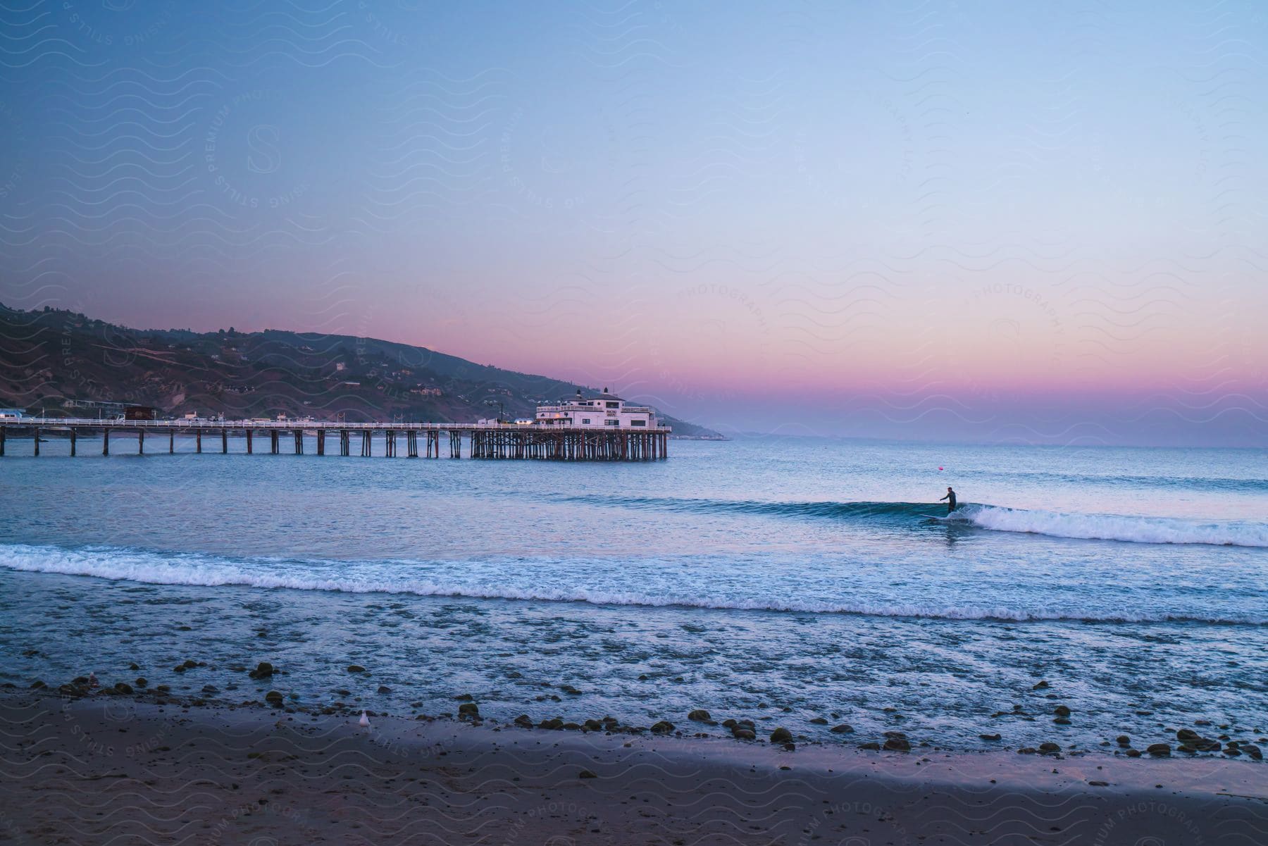 a surfer rides some waves at sunset.