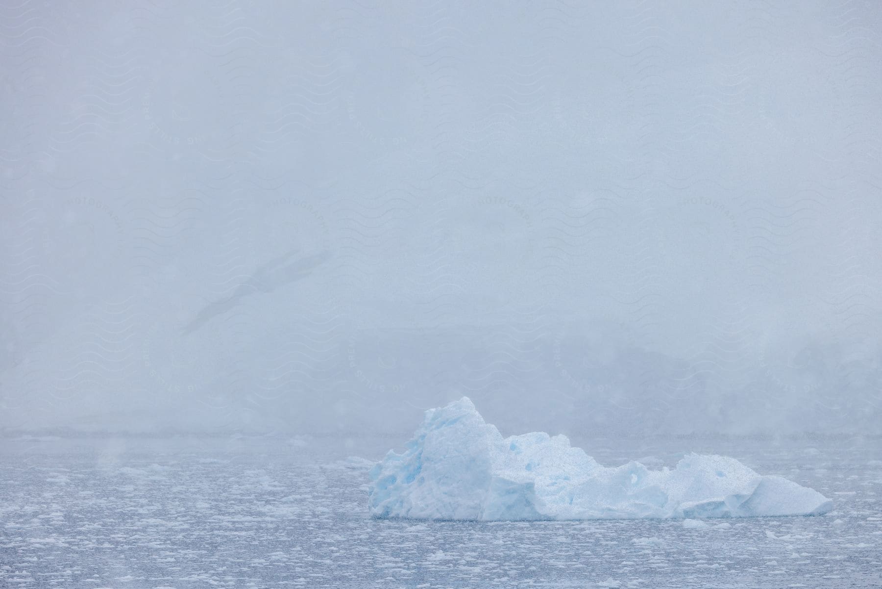 An iceberg drifting in the Arctic Sea amid a foggy atmosphere.