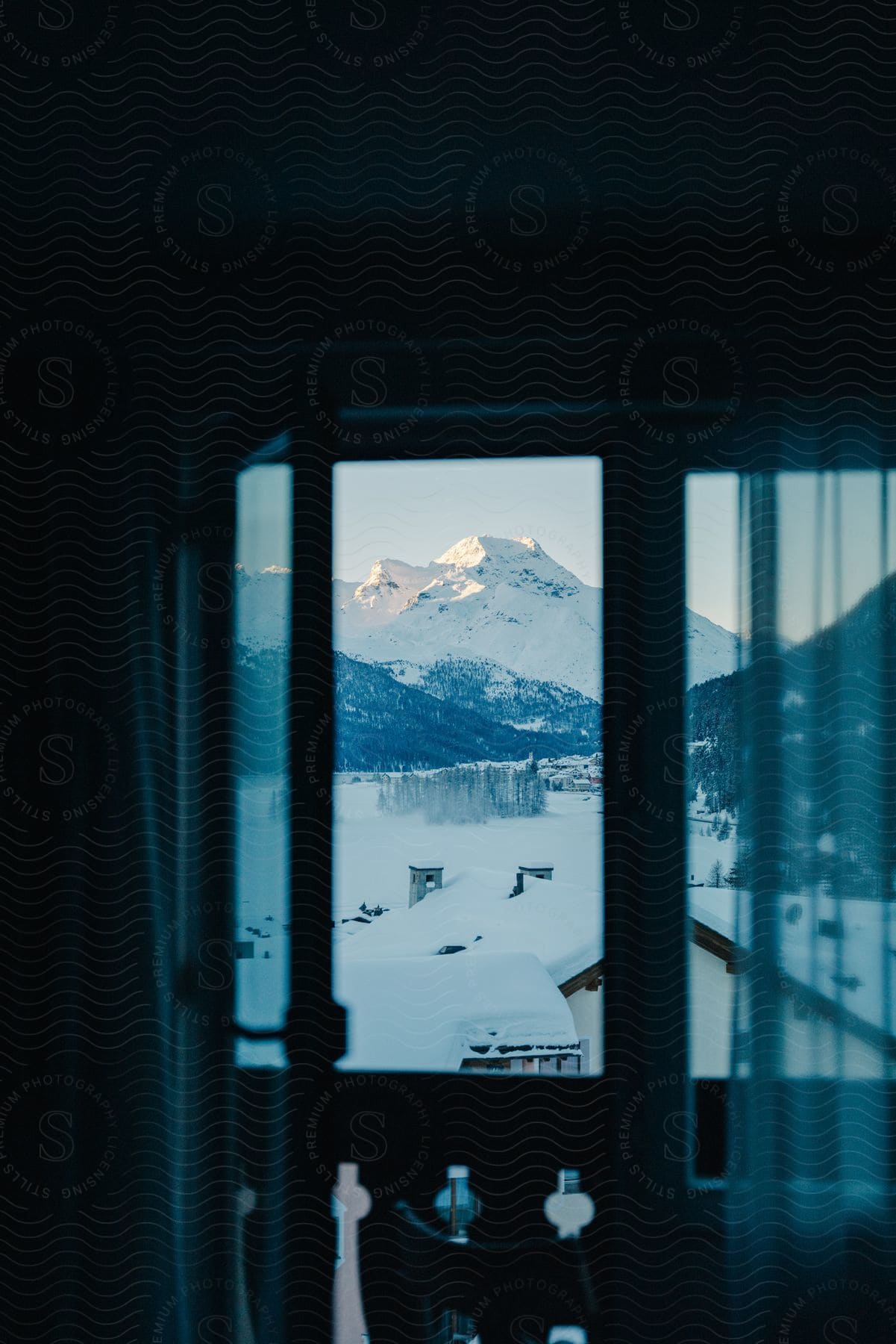 View from the window of urban houses on a snow-covered ground and mountains around