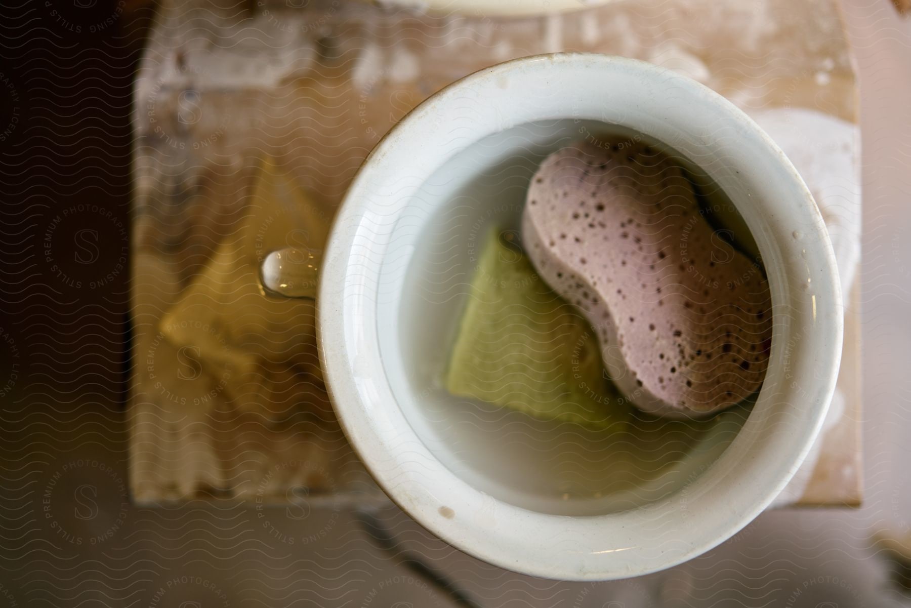 a yellow sponge sitting in a blue ceramic cup filled with clear water