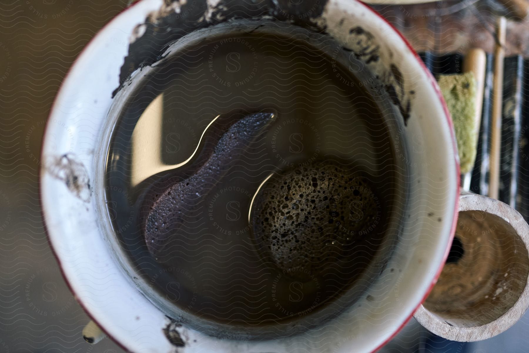 Two sponges sit in a cup filled with black liquid.