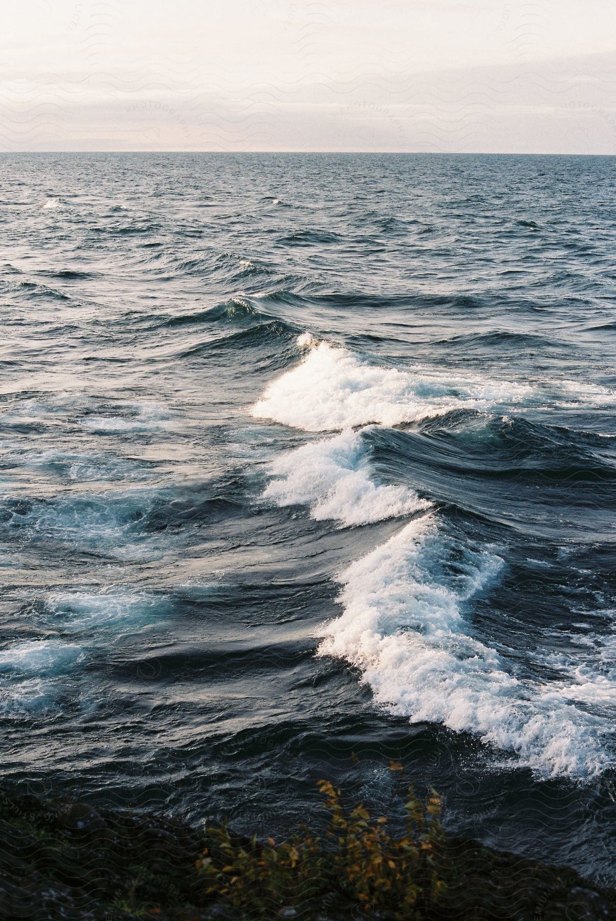 Sea with waves in shades of blue and a partially cloudy sky.