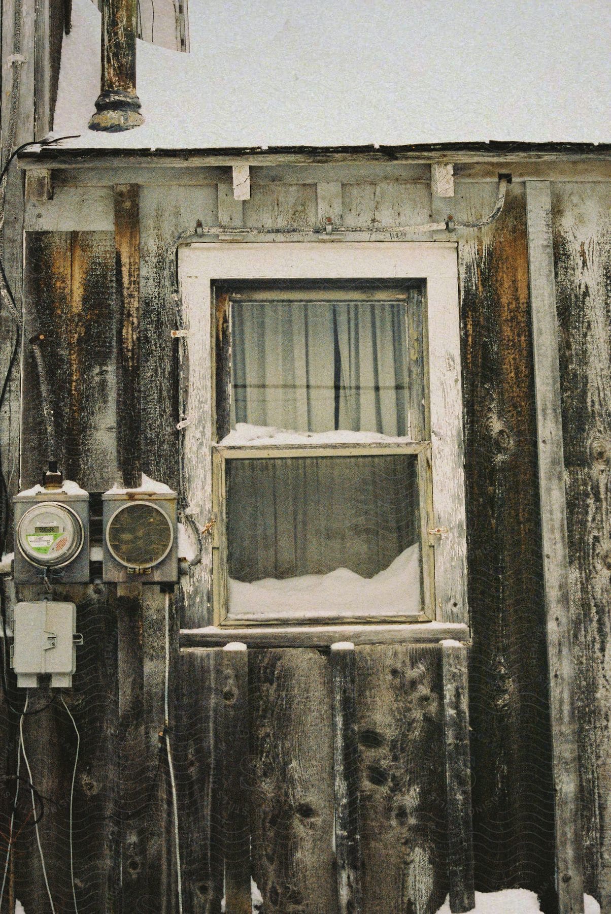 Exterior window on the side of a rustic wood slate building on a winter day.