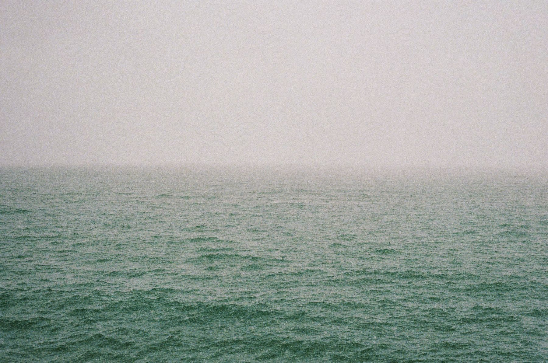 Green and calm ocean waters on a foggy morning.