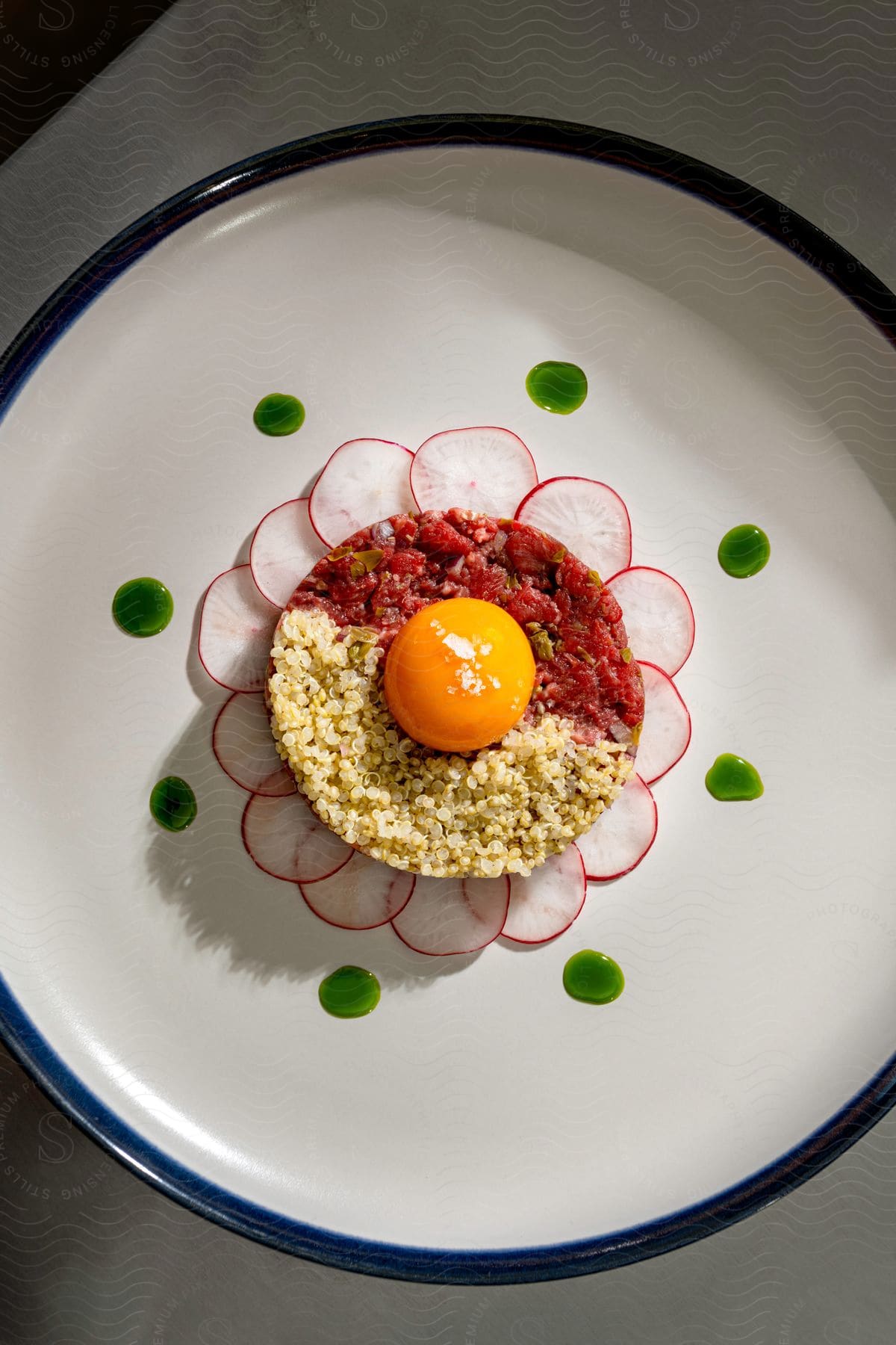 An egg yolk and a sliced radish are arranged like a flower petal on a dinner plate.