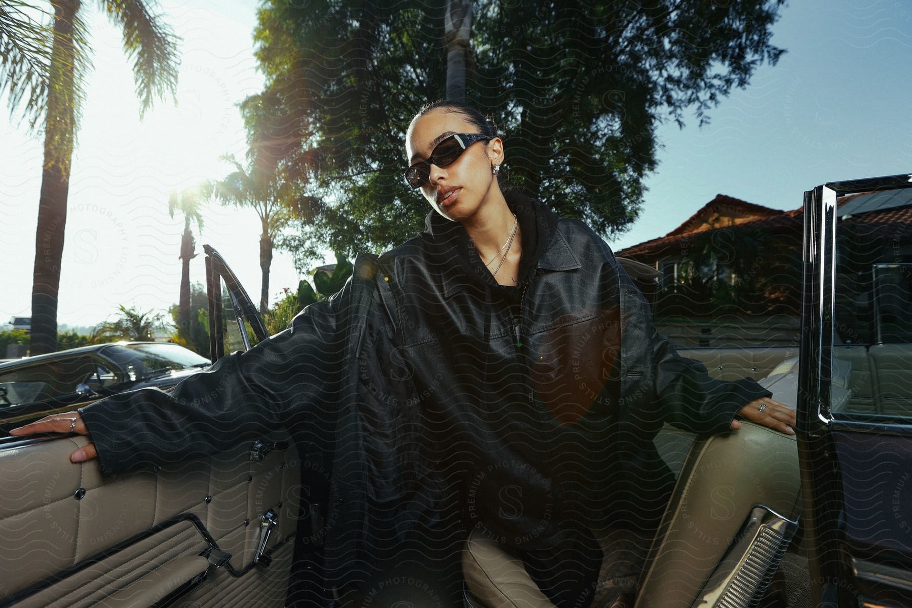 A woman posing for a photo while leaving a luxury car.