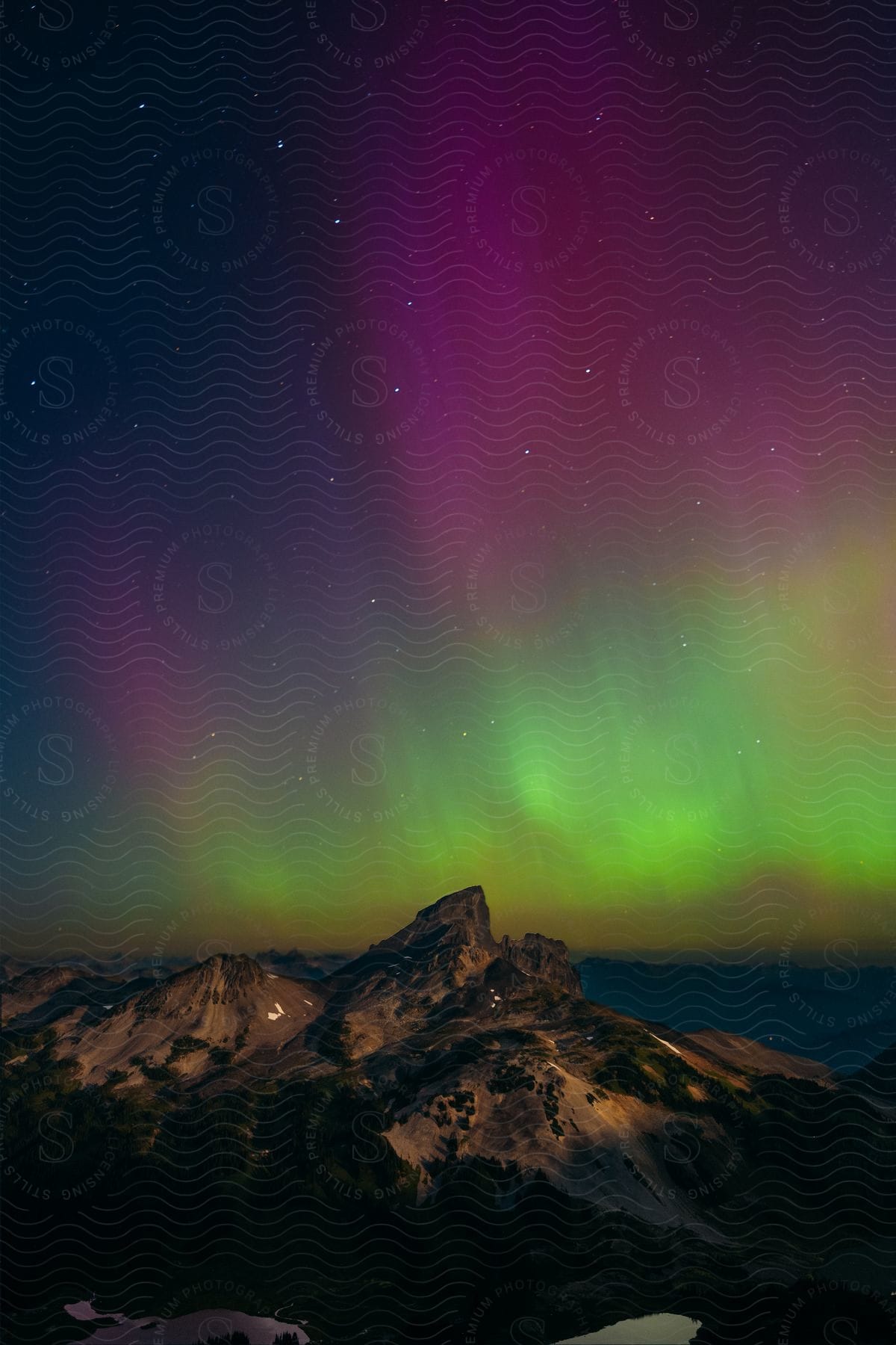 Landscape of mountain ranges at night and a sky with Northern Lights